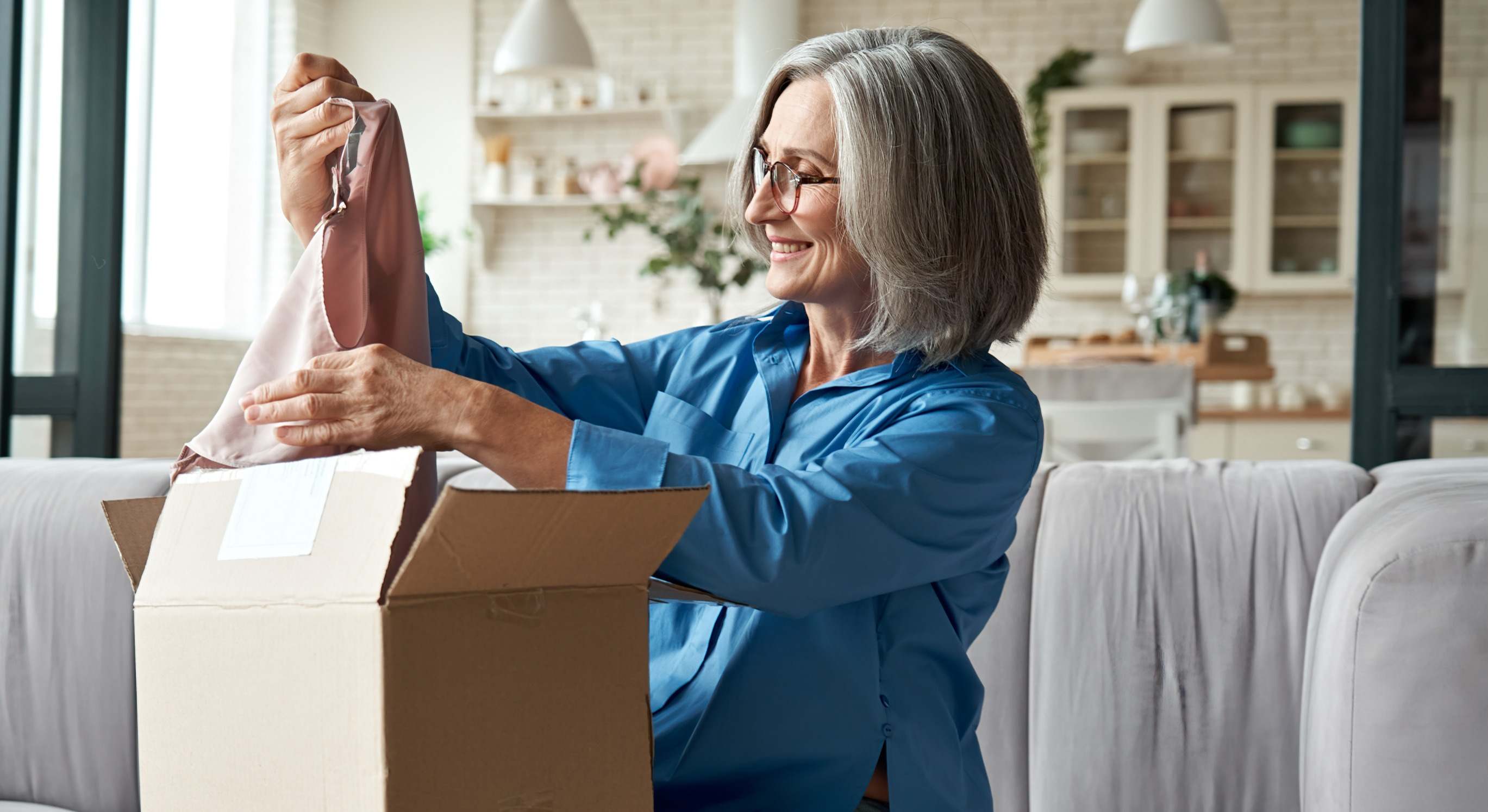 Imagen de recurso de una mujer abriendo una caja de una compra online.