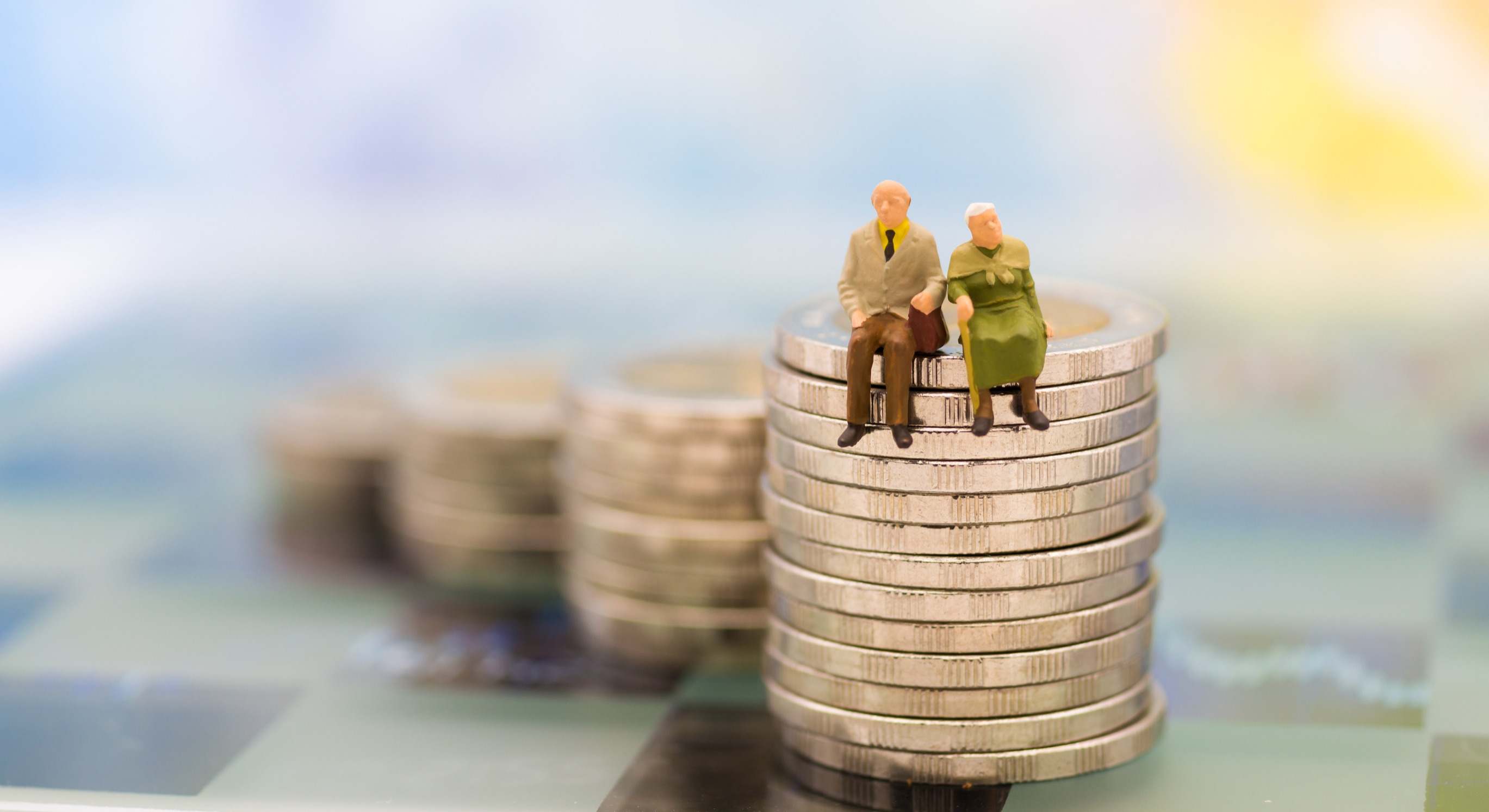 Dos jubilados sentados sobre un montón de monedas