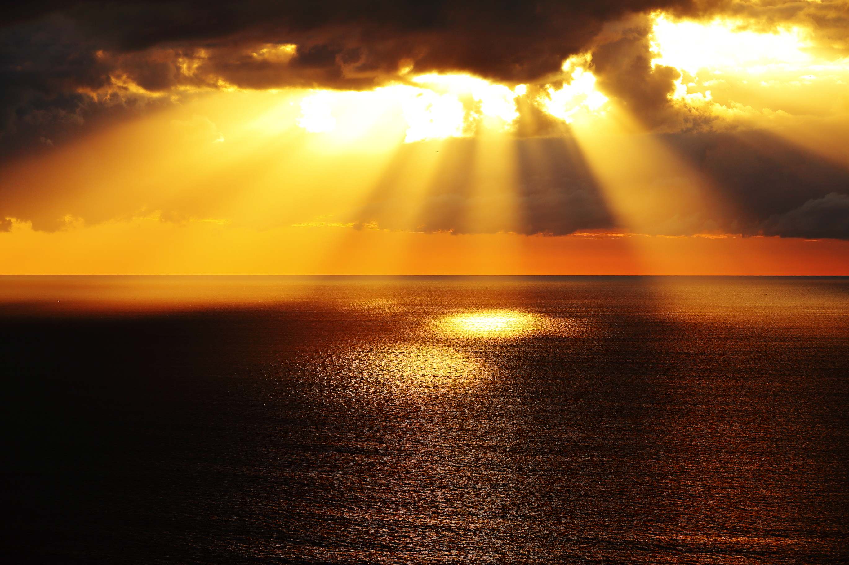 Rayos de sol asomando tras las nubes sobre el mar