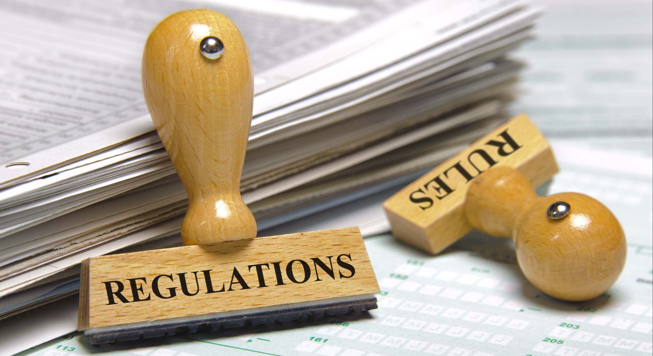 Sellos con la palabra regulación delante de un motón de papeles