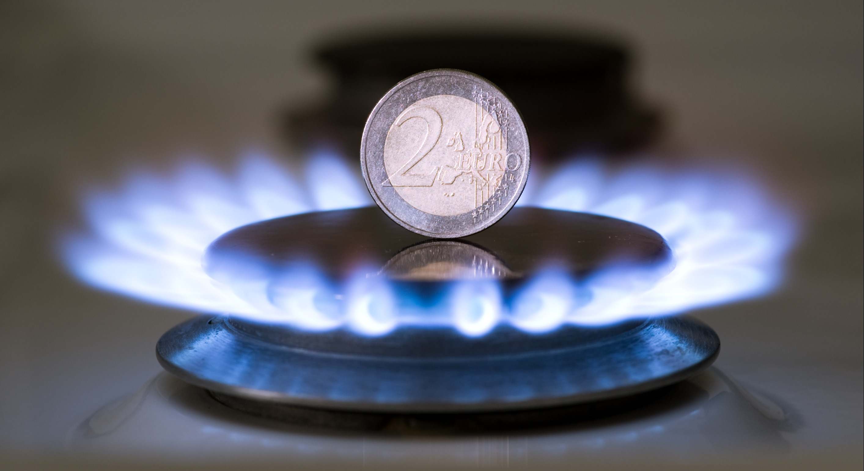 Una cocina de gas con una moneda de dos euros entre el fuego
