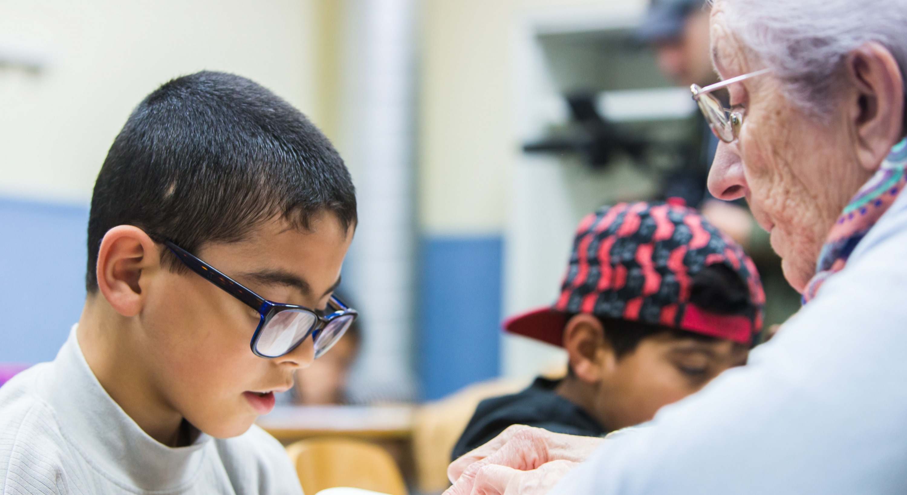 Una persona mayor voluntaria ayuda a un niño con sus estudios. 