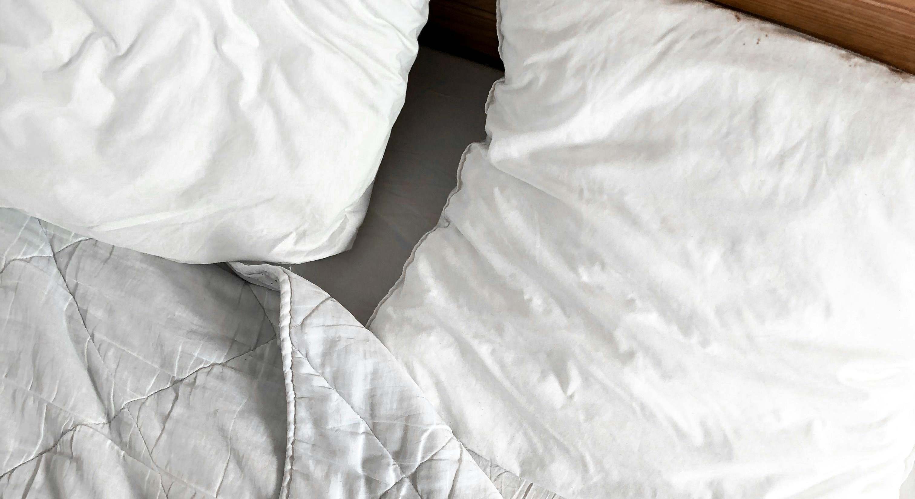 Una cama con una sábana y dos almohadas