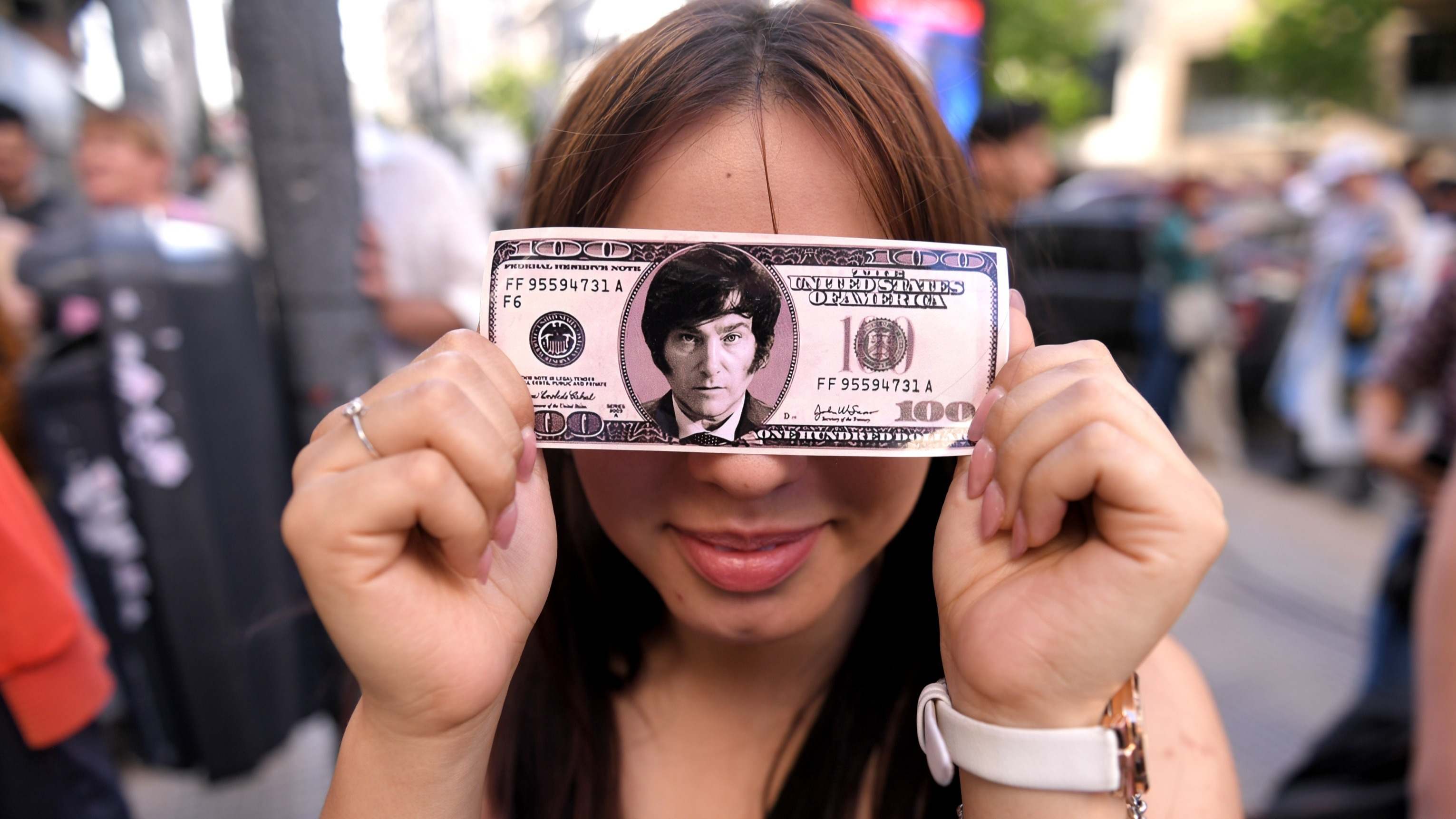 Una simpatizante de Milei enseña un dólar con su rostro