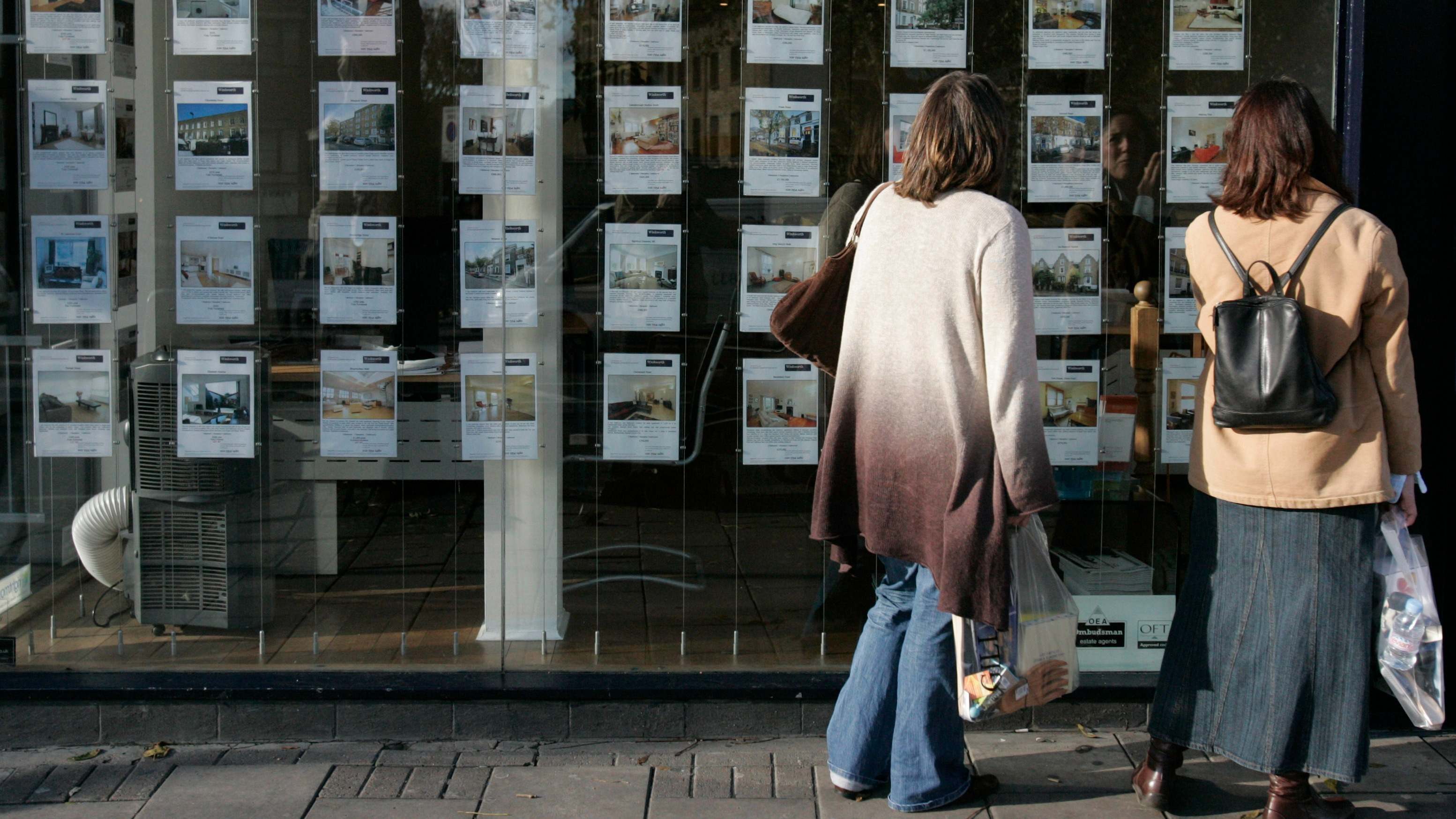 Mujeres mirando el escaparate de una agencia inmobiliaria | iStock 