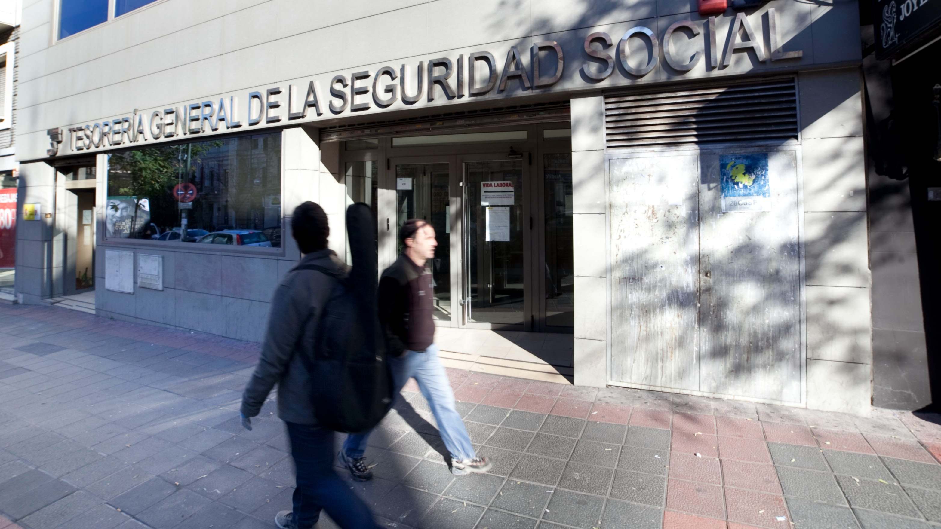 Dos personas pasan por delante de una oficina de la Tesorería General de la Seguridad Social