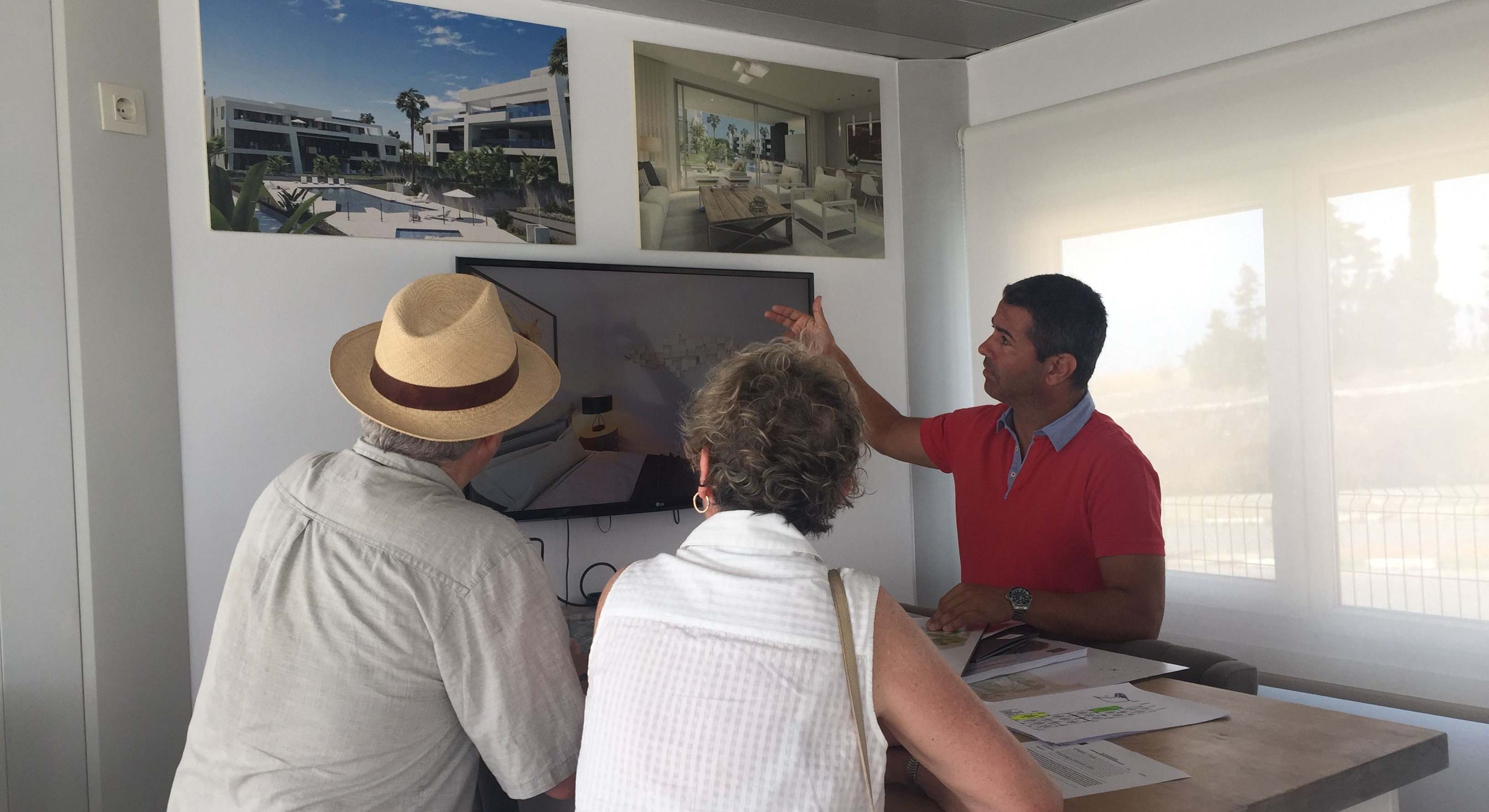 Un comercial muestra a un matrimonio extranjero una promoción de AEDAS Homes en la Costa del Sol