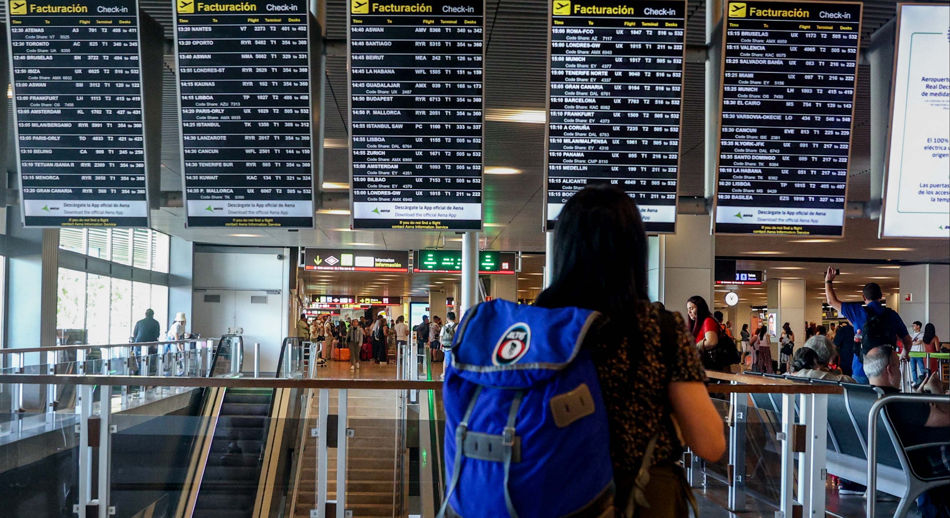 Un turista mirando el panel de vuelos en un aeropuerto
