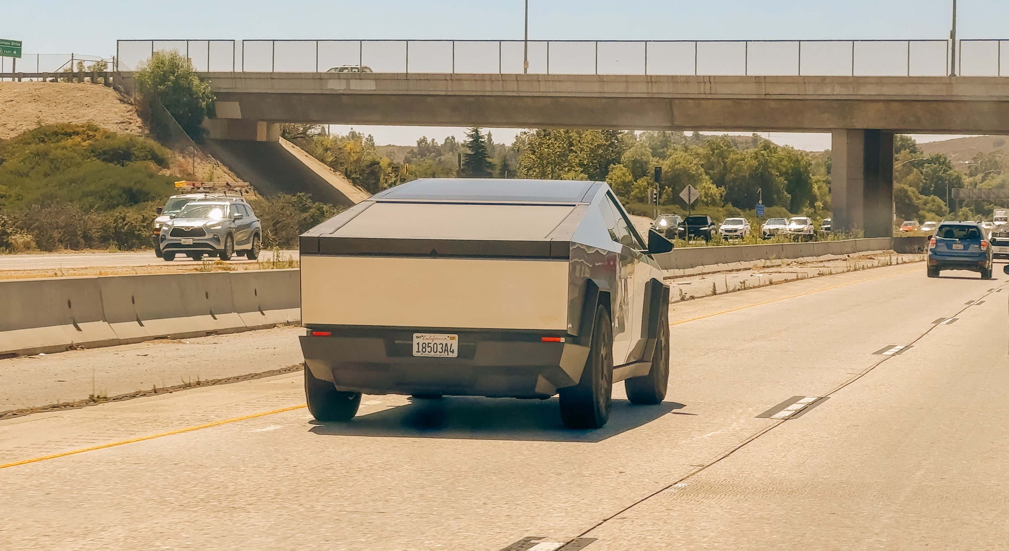El Tesla Cybertruck circula por una concurrida autopista de California bajo un cielo azul claro