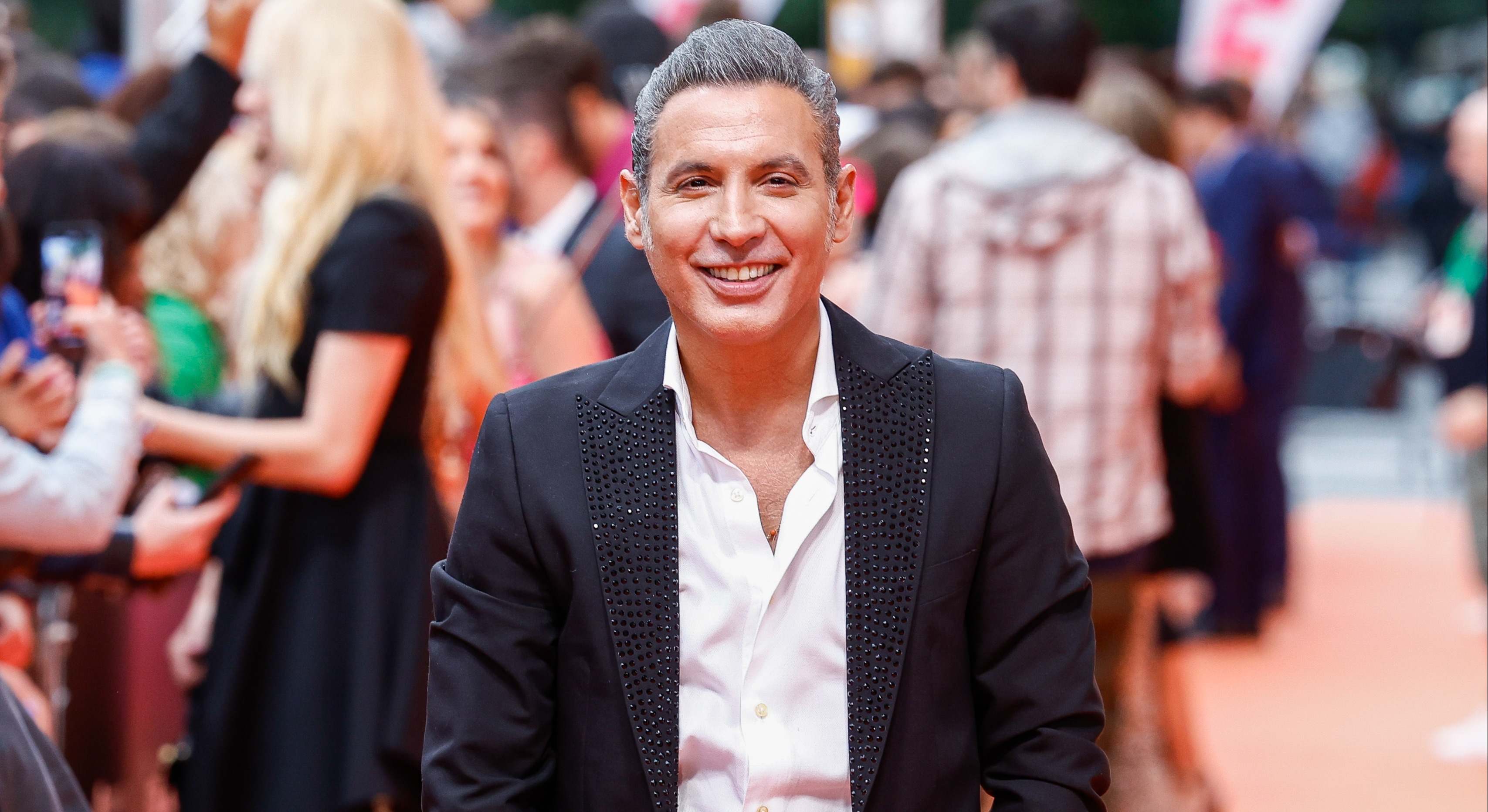 El cantante pitingo con camisa blanca y chaqueta negra