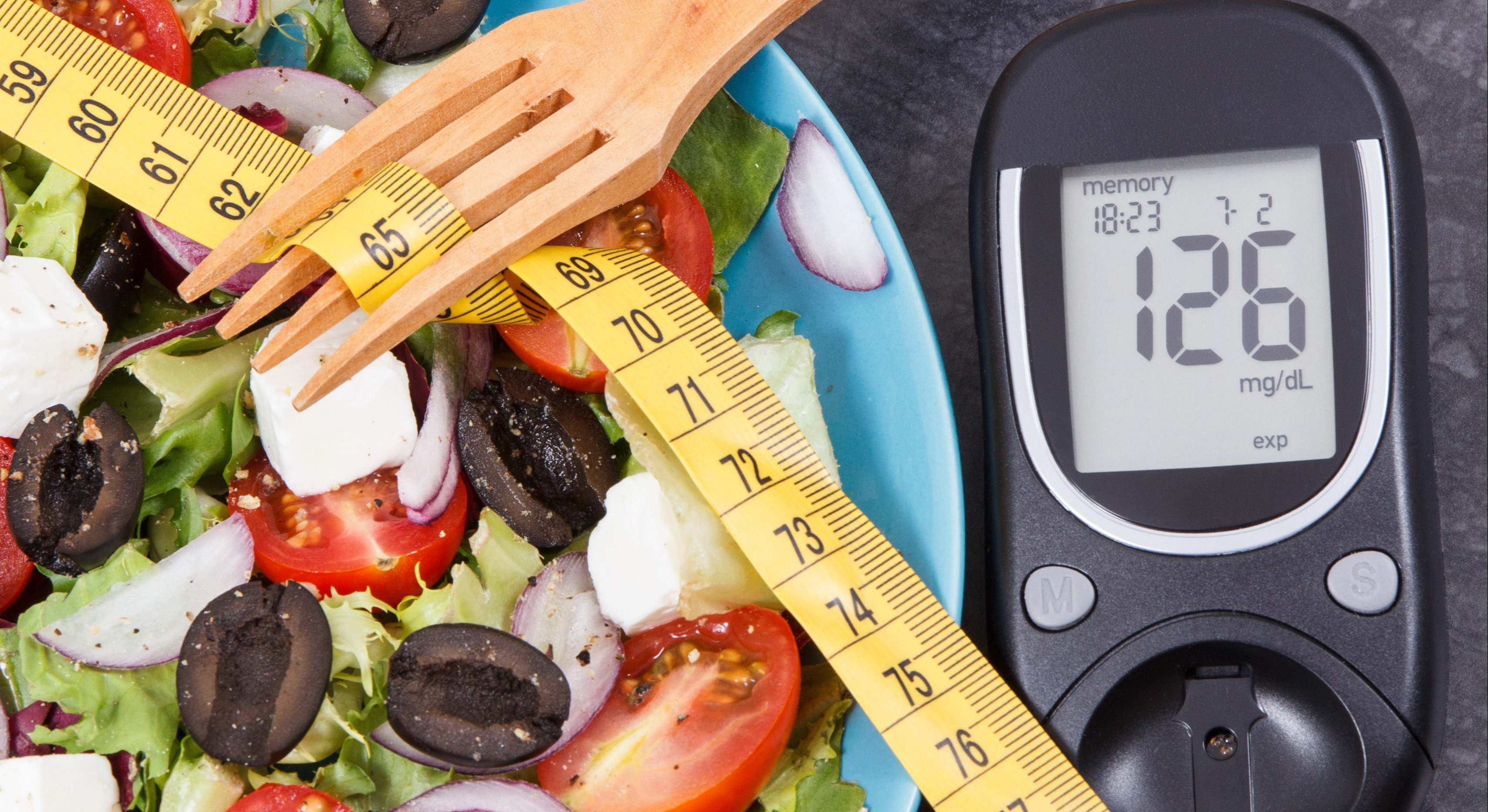 Medidor de glucosa con nivel de azúcar, una cinta de medir y una ensalada griega