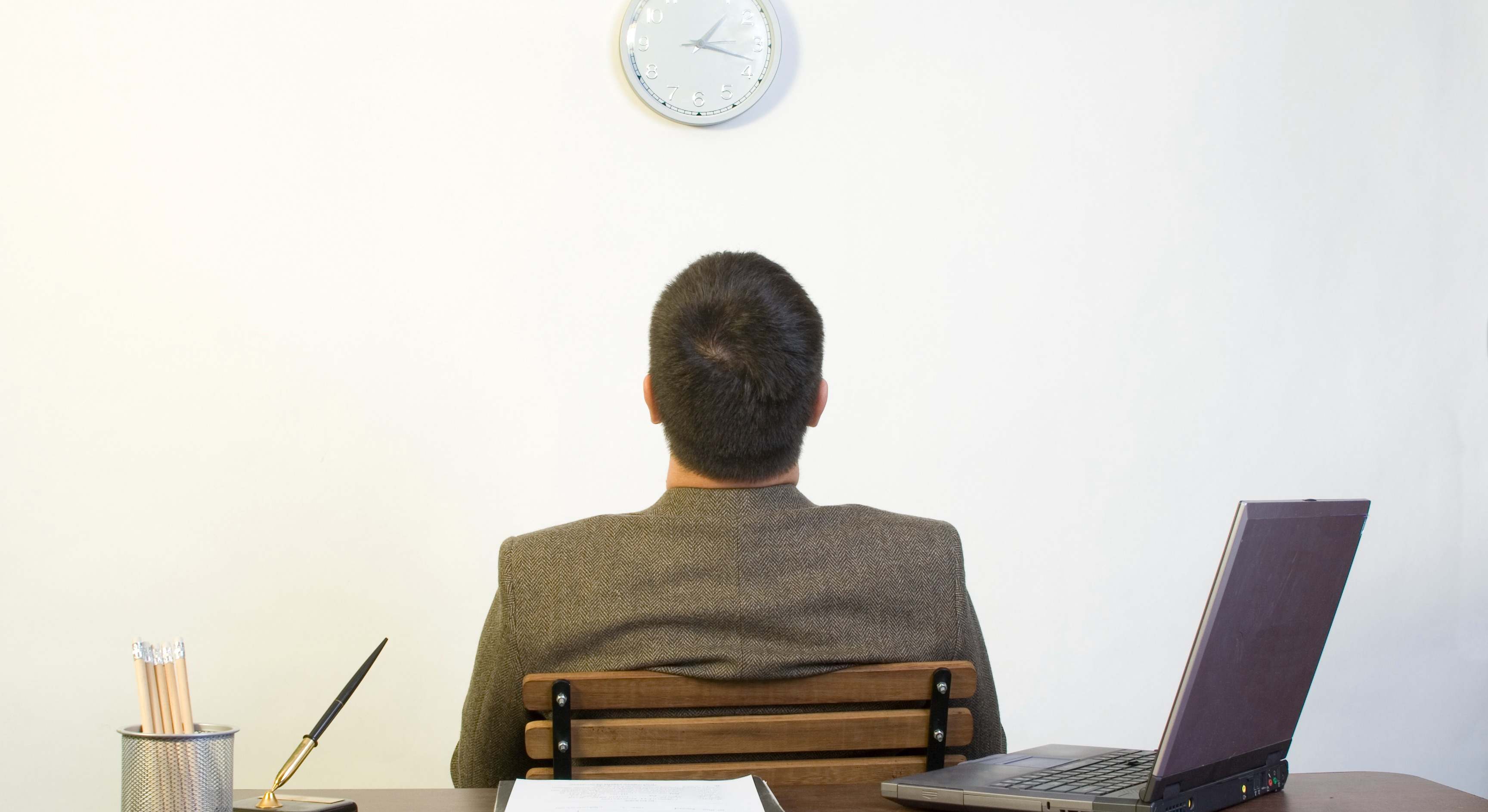 Persona trabajando en un despacho mirando el reloj de la pared