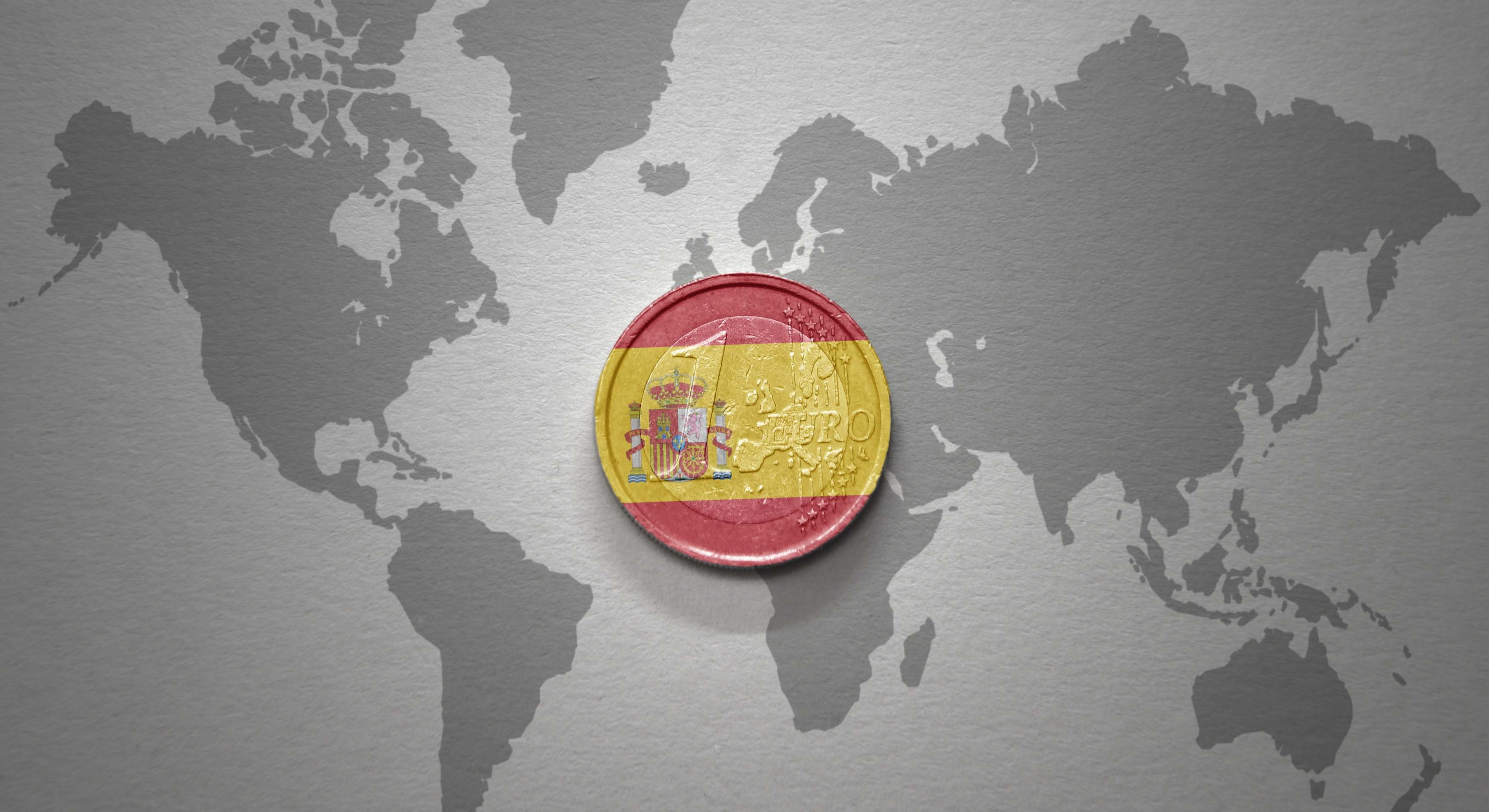 Mapamundi con una moneda de euro coloreada con la bandera de Espaaña