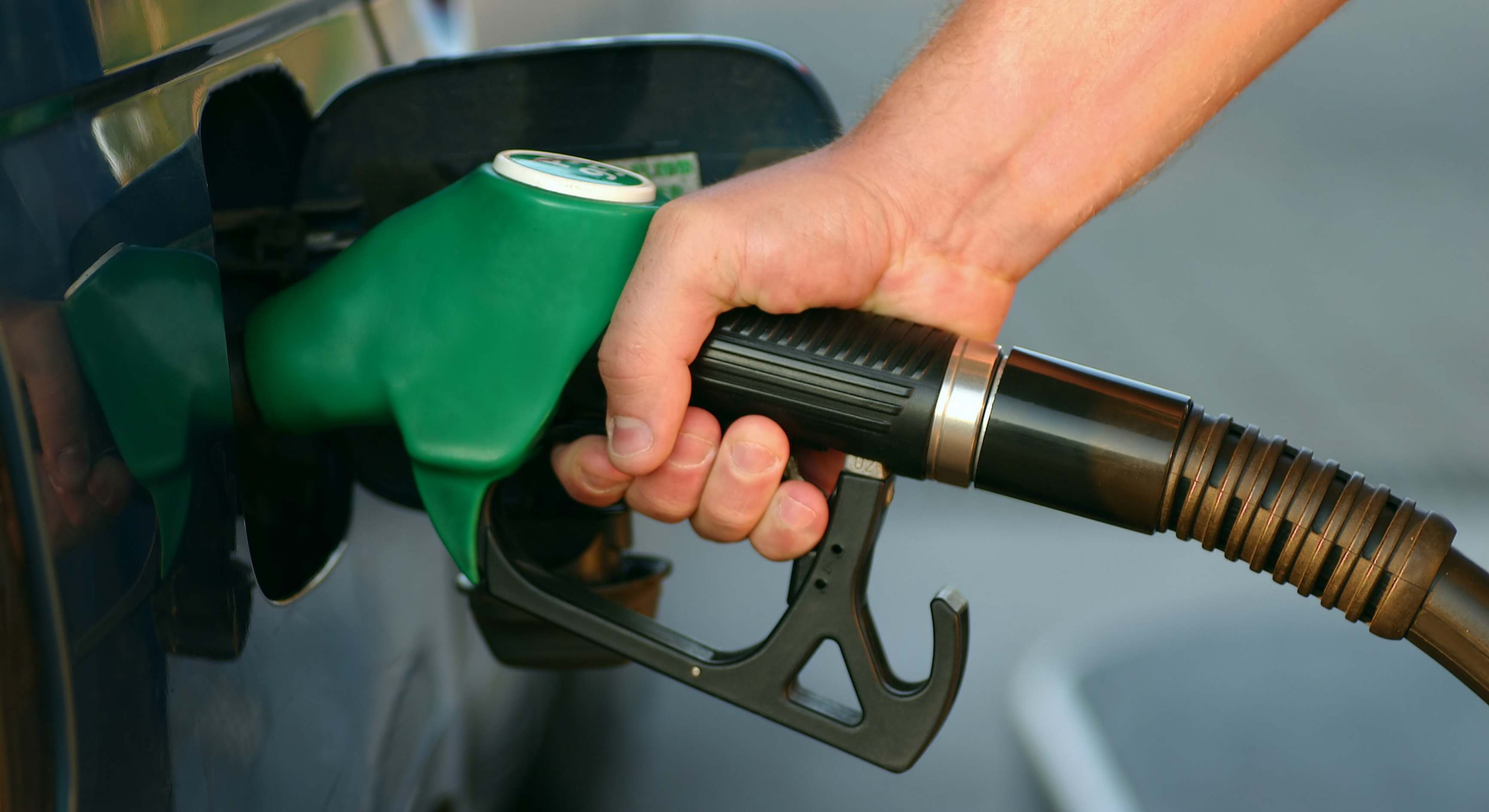 Un hombre usando un surtidor de gasolina para llenar su coche del combustible