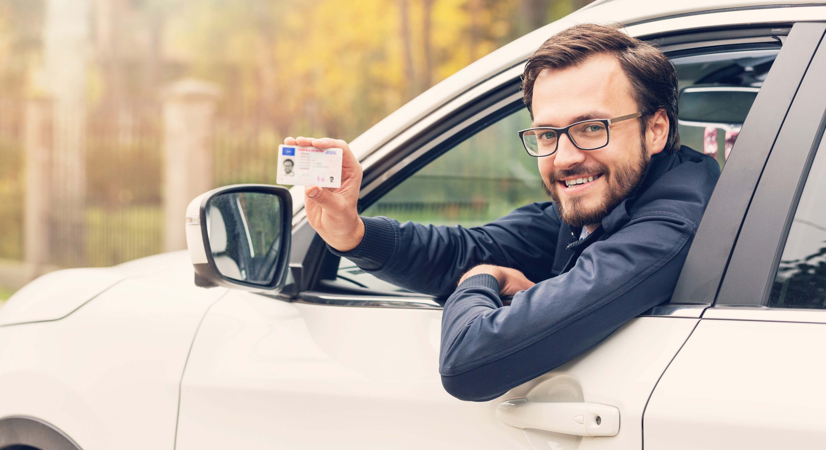 Conductor con gafas sentado en el coche y mostrando su carnet de conducir
