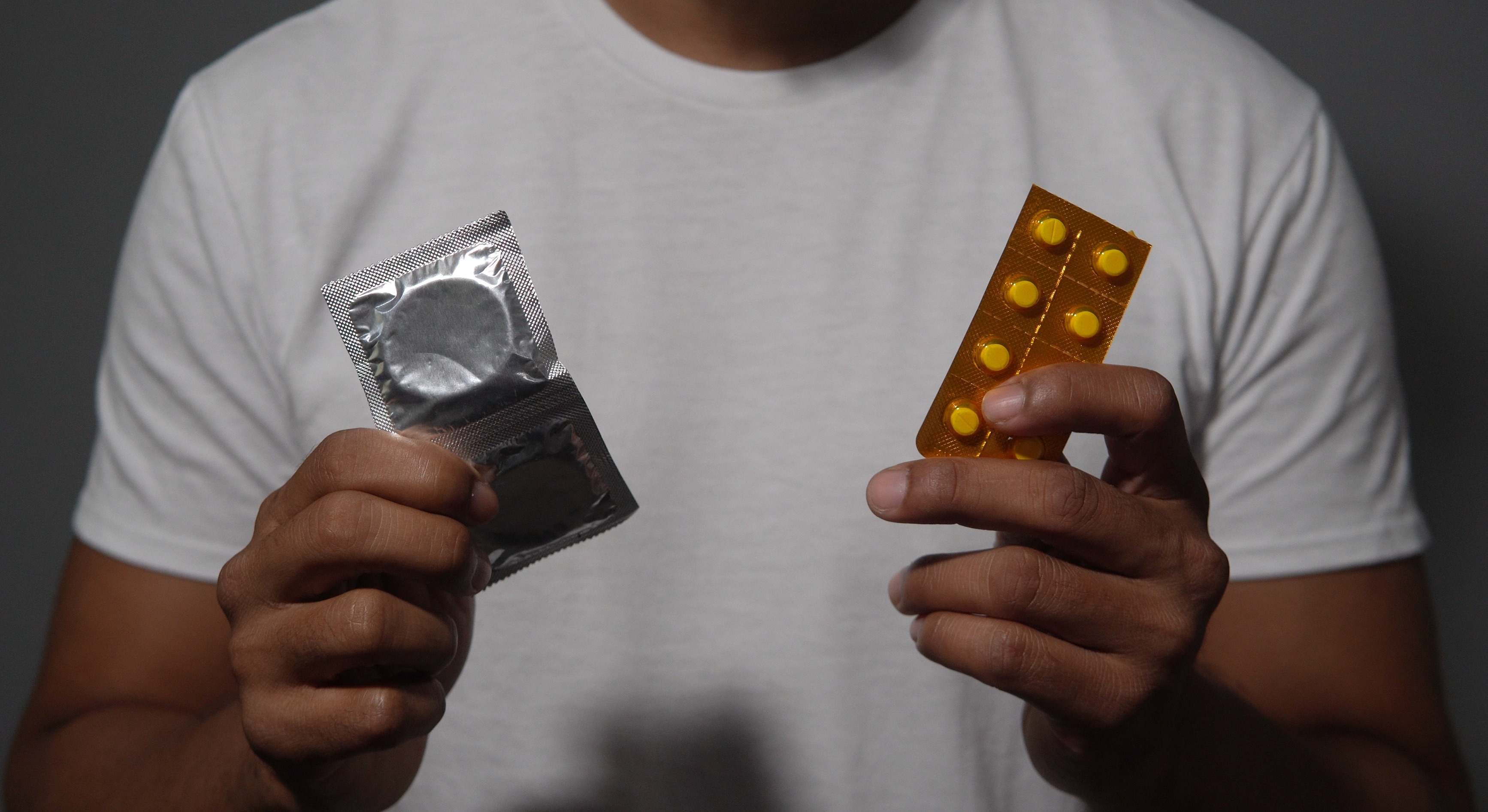 Hombre sosteniendo dos métodos anticonceptivos diferentes