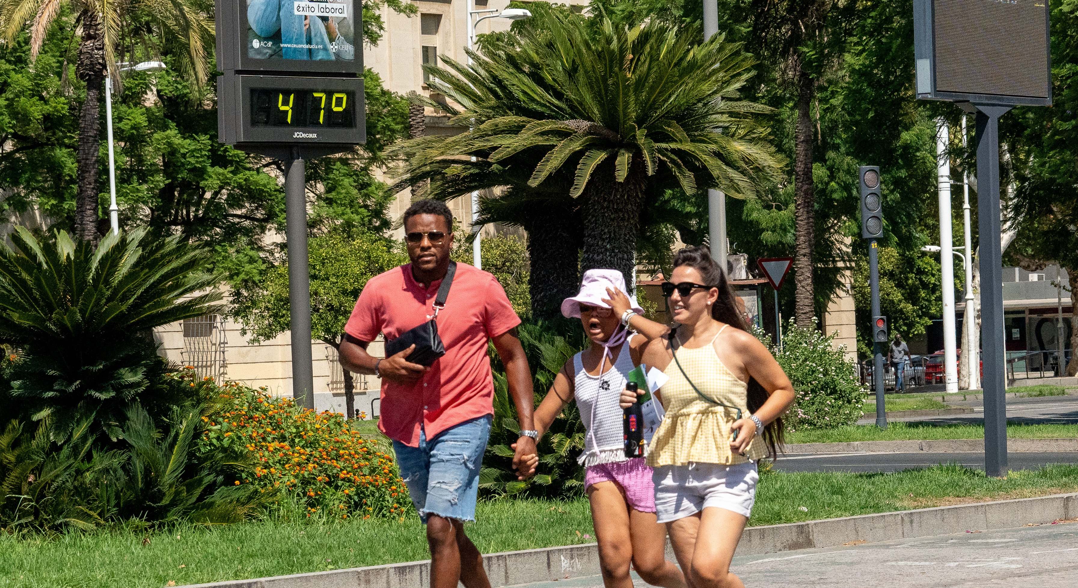 Personas al lado de un termómetro en las calles de Sevilla a 47 grados de temperatura