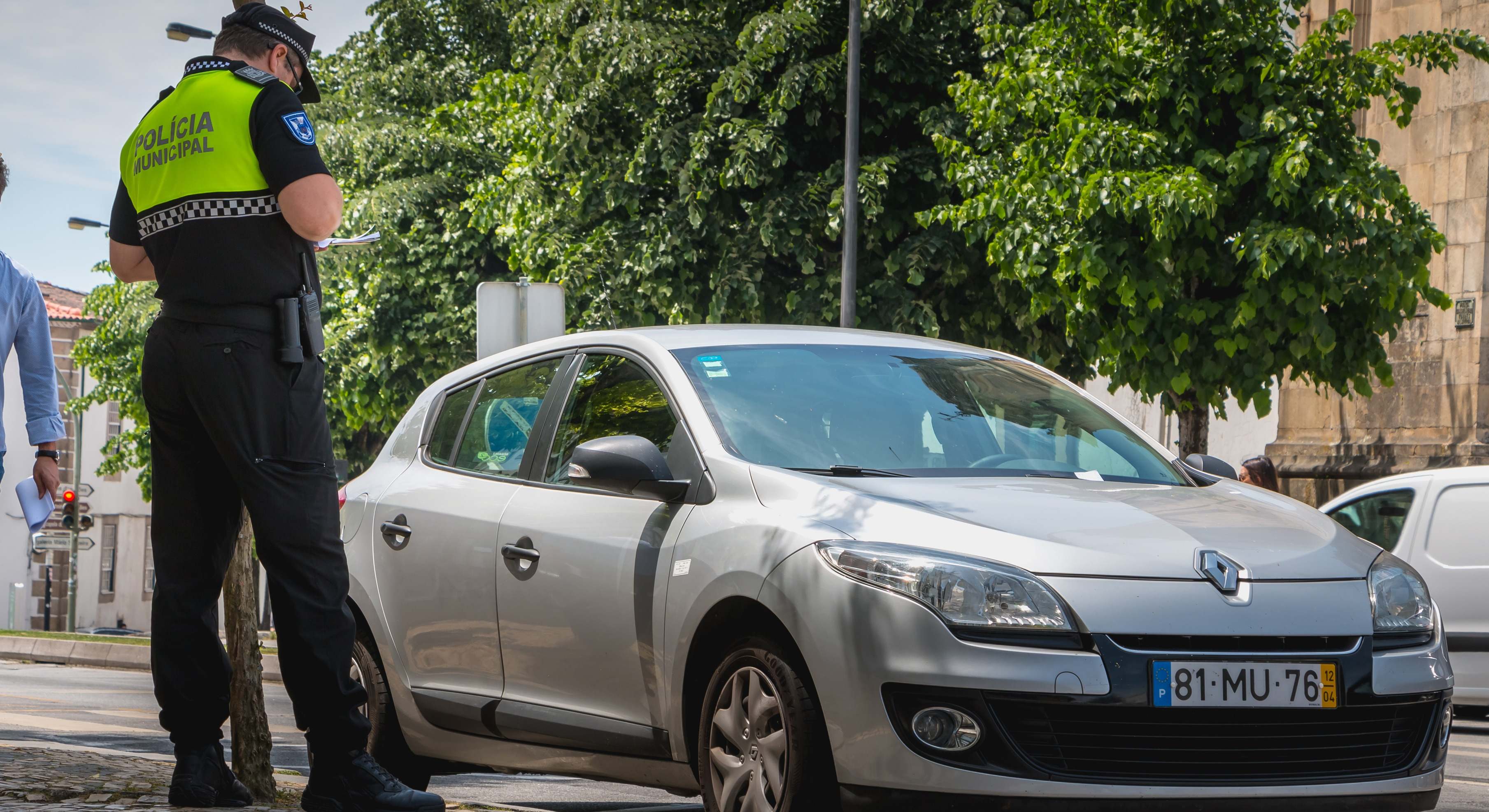 Un policía comprueba y pone una multa de tráfico a un coche en el centro de la ciudad