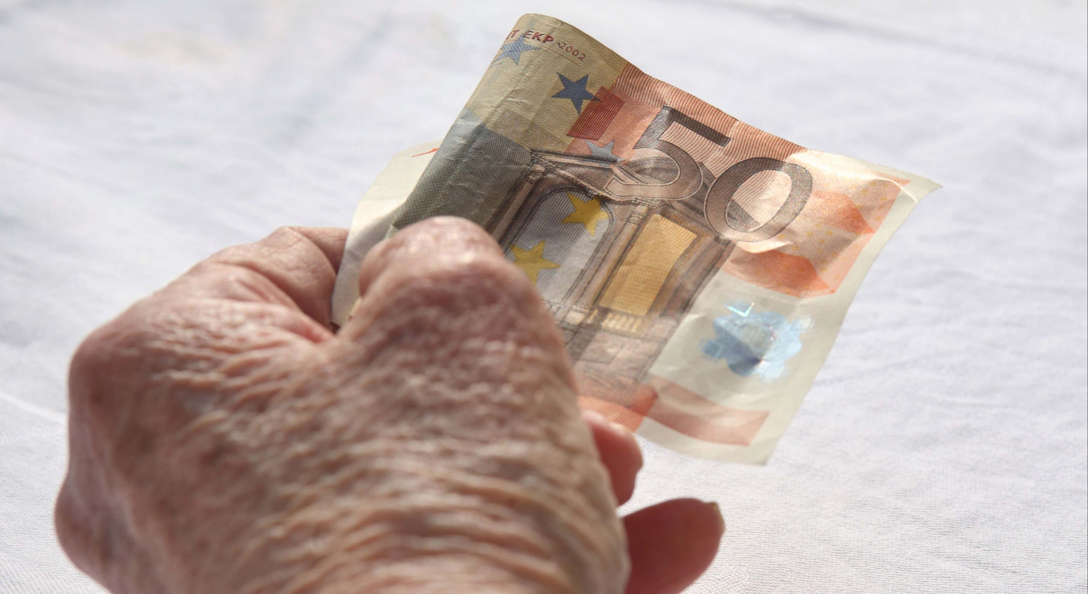 Persona mayor sosteniendo un billete de 50 euros
