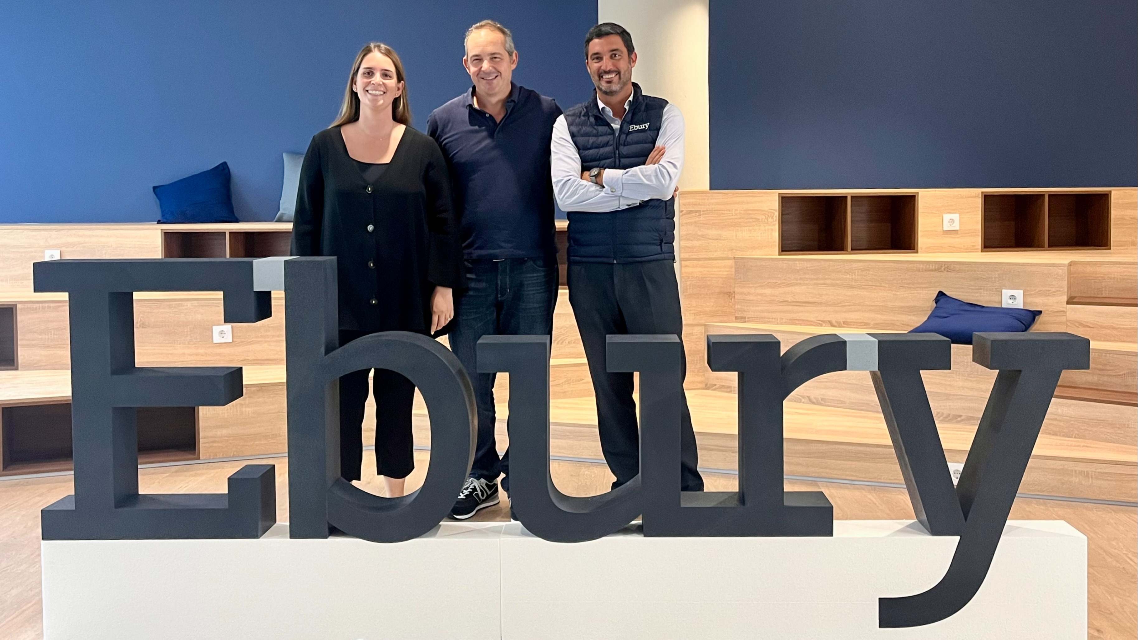 Parte del equipo directivo de Ebury posa tras un cartel de la empresa