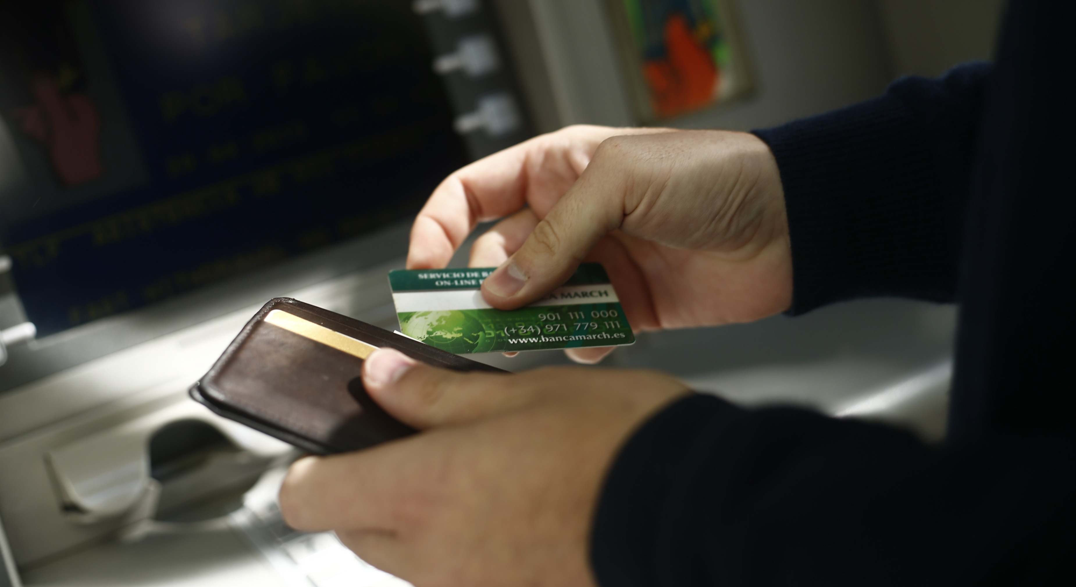 un cliente saca su tarjeta de la cartera para usar un cajero