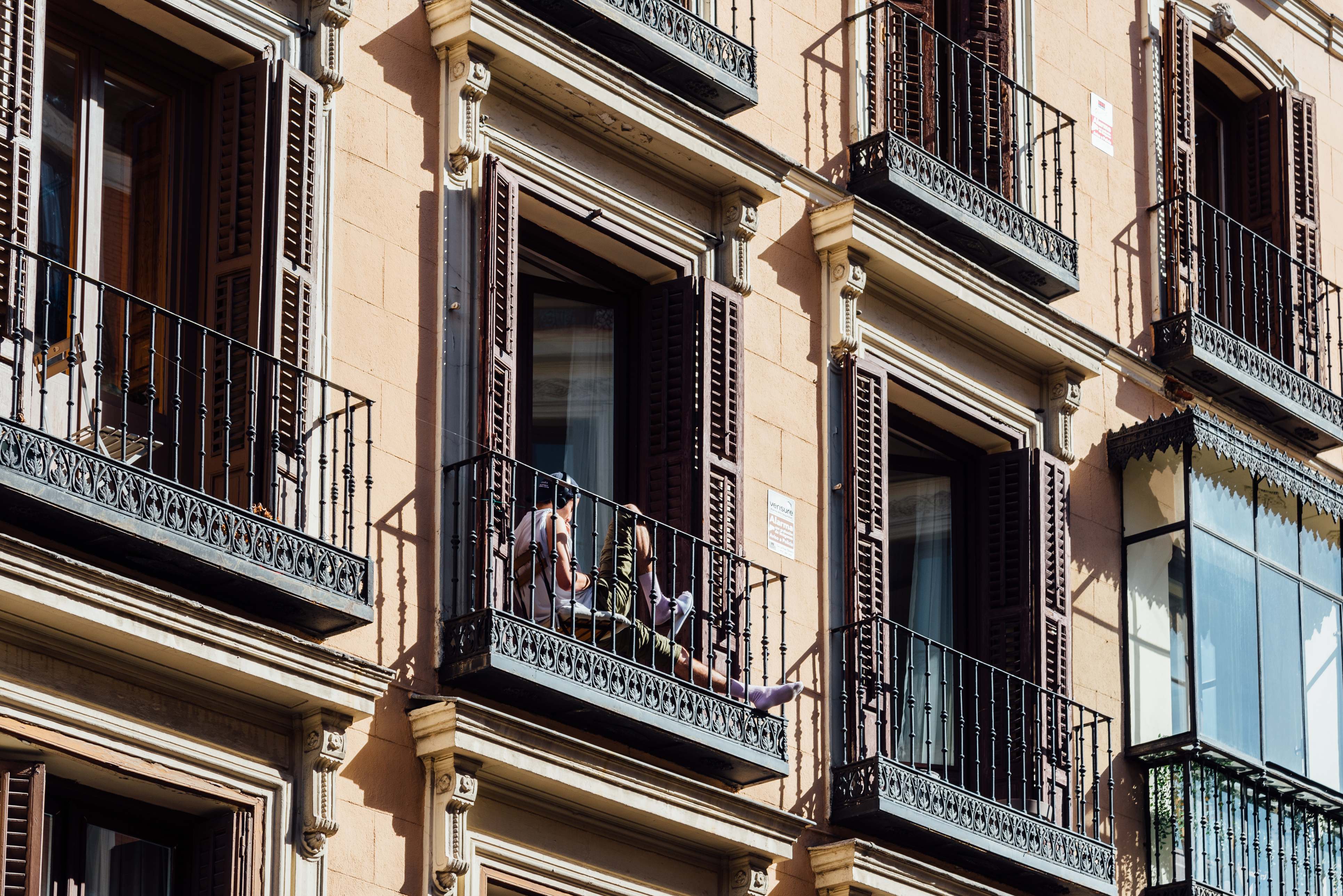 Hombre sentado en el balcón de un antiguo edificio en centro histórico de Madrid | iStock