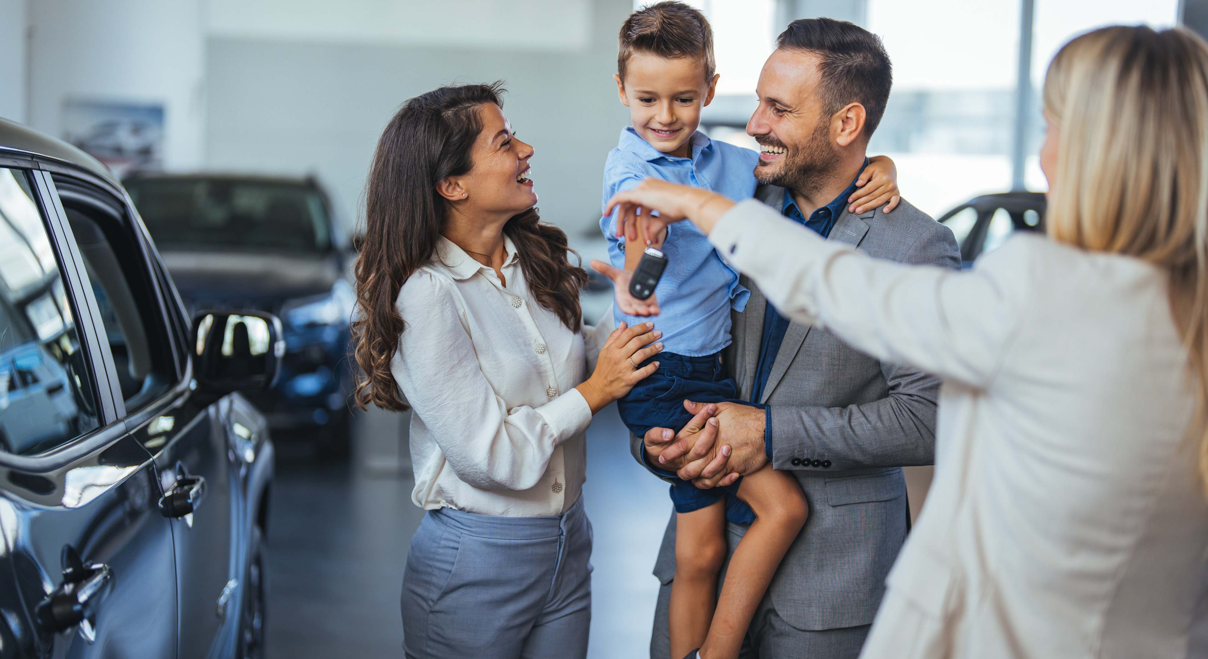 Familia feliz sosteniendo las llaves de su nuevo automóvil en el concesionario