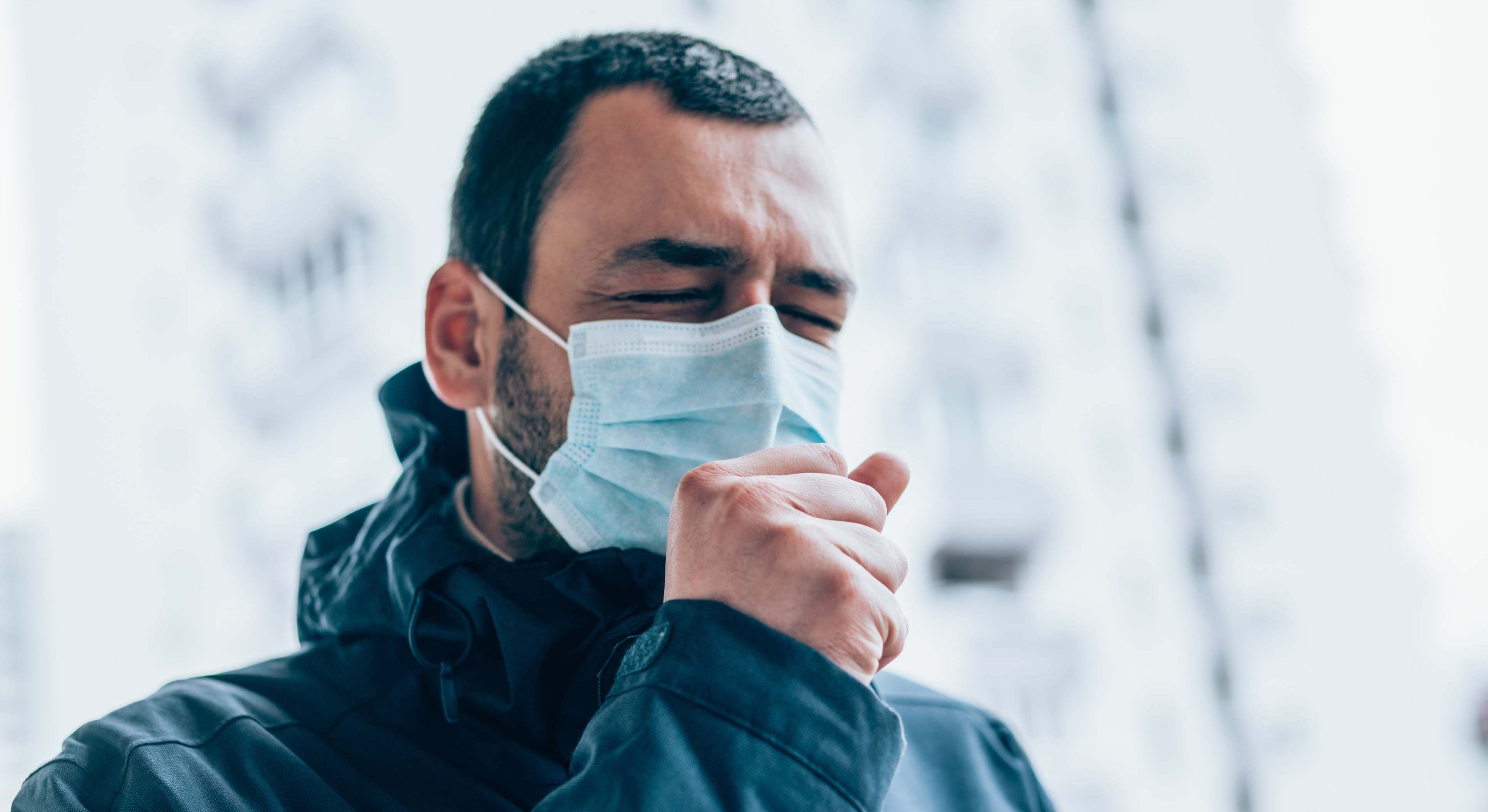Hombre tosiendo con mascarilla