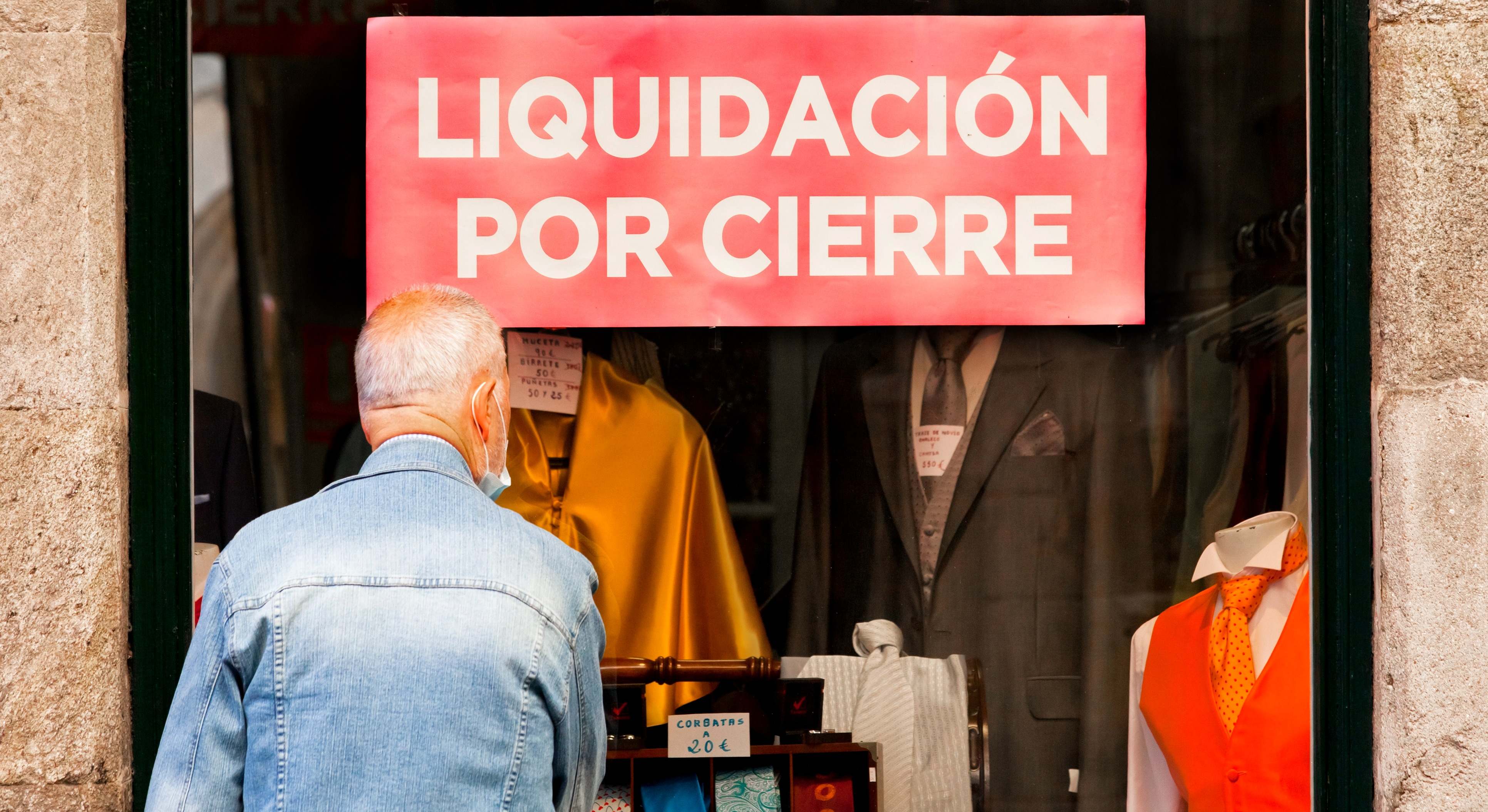 Un hombre mira el escaparate de una tienda en liquidación por cierre