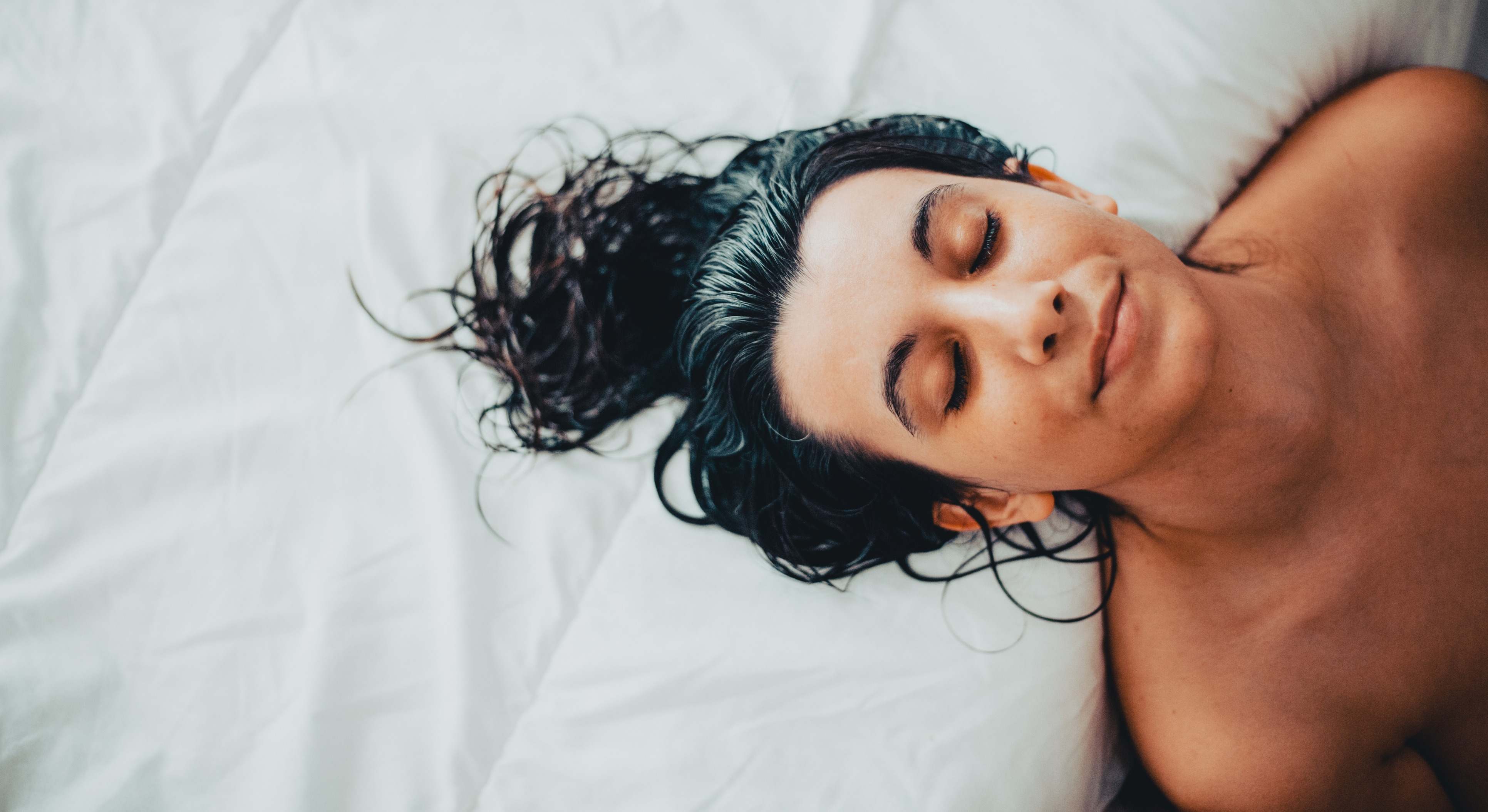 Una mujer recostada en la cama con el pelo mojado. / Foto: iStock
