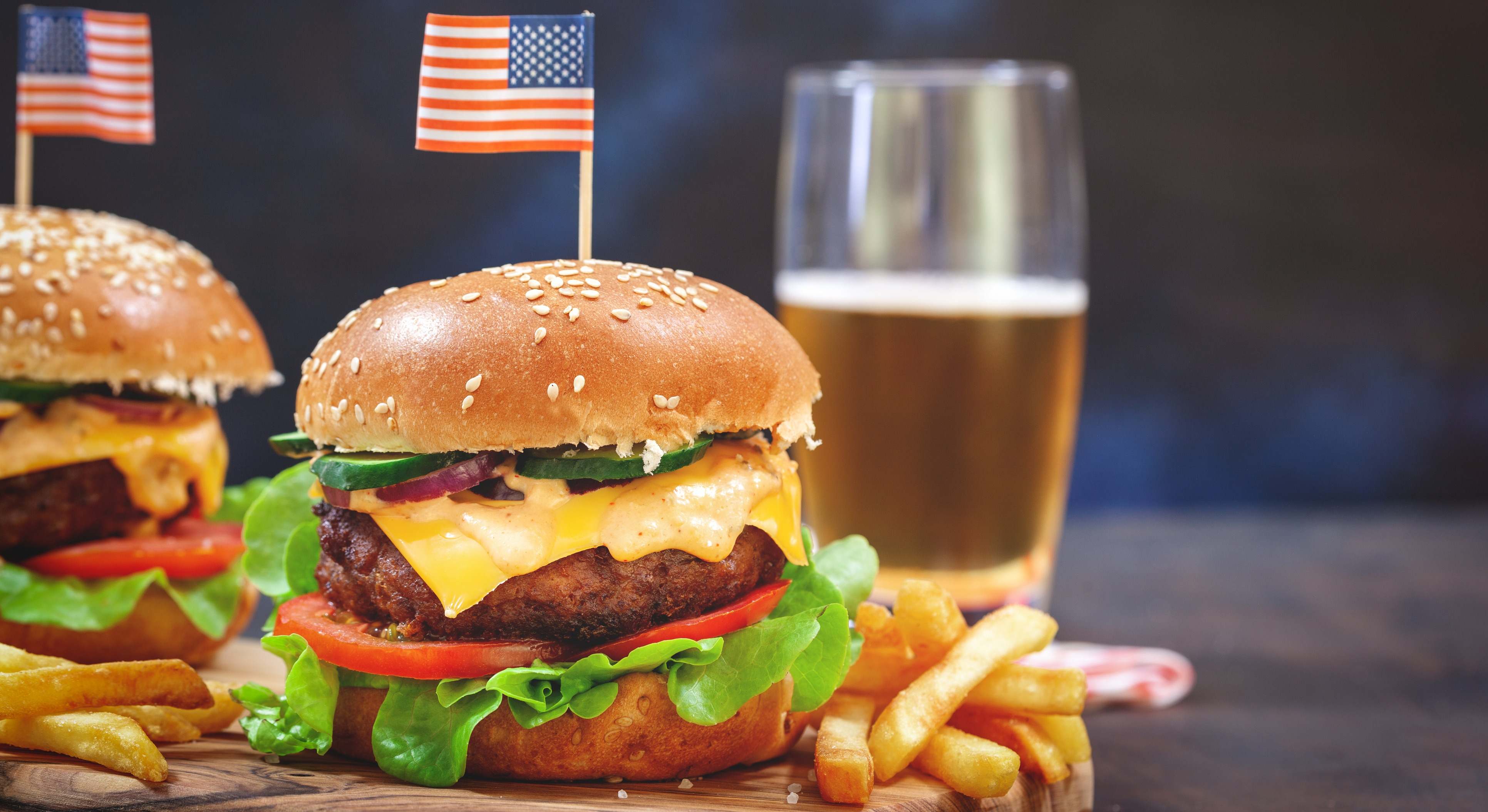 Hamburguesas con una bandera de EEUU y un vaso de cerveza en el fondo. Foto: iStock