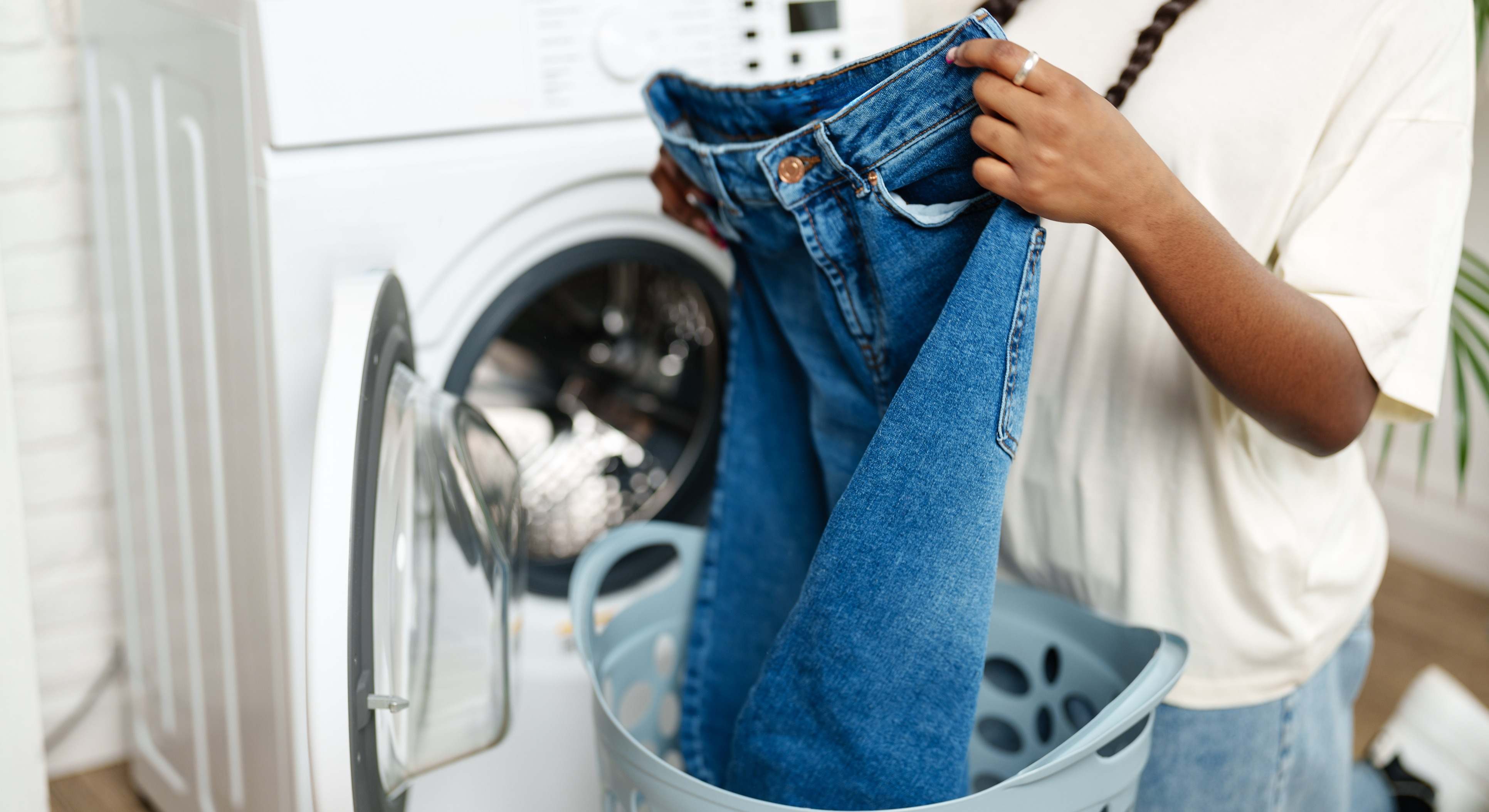 Una mujer saca los pantalones vaqueros de la lavadora. / Foto: iStock