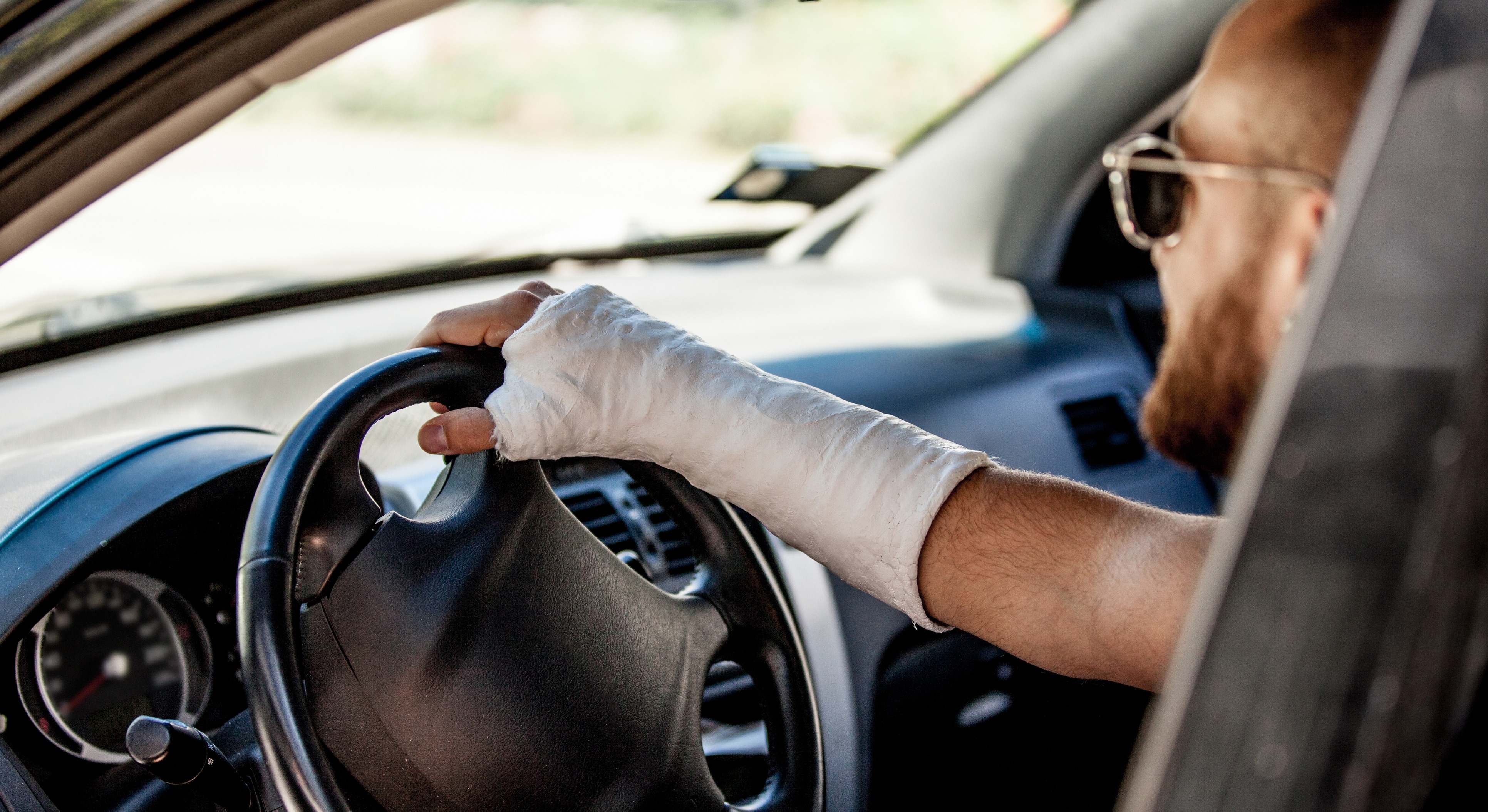 Conductor conduciendo con una escayola en el brazo