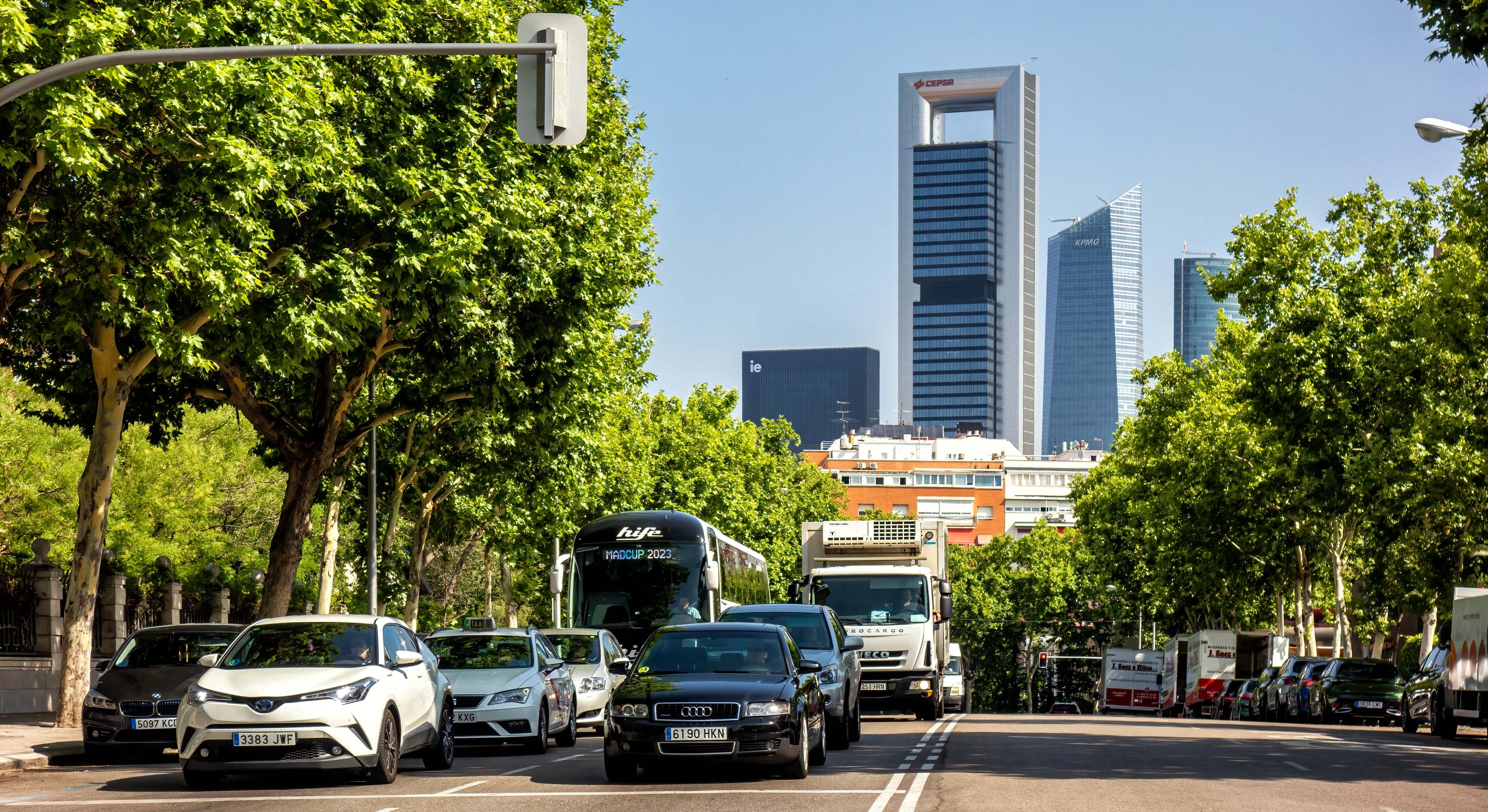 Vehículos esperando a que un semáforo se ponga verde en una calle de la ciudad de Madrid con las emblemáticas torres a sus espaldas