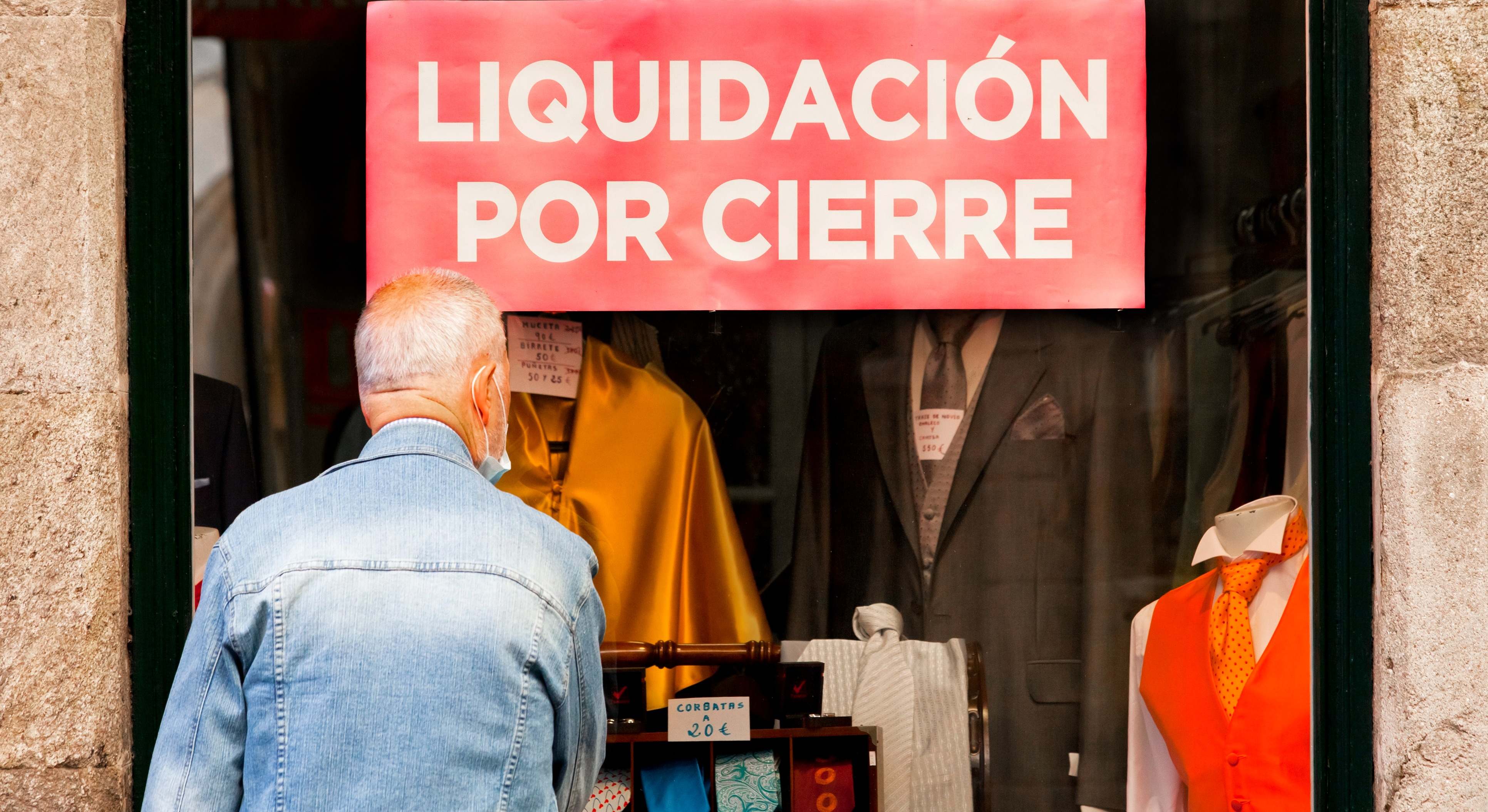 Un hombre mira el escaparate de una tienda en liquidación por cierre