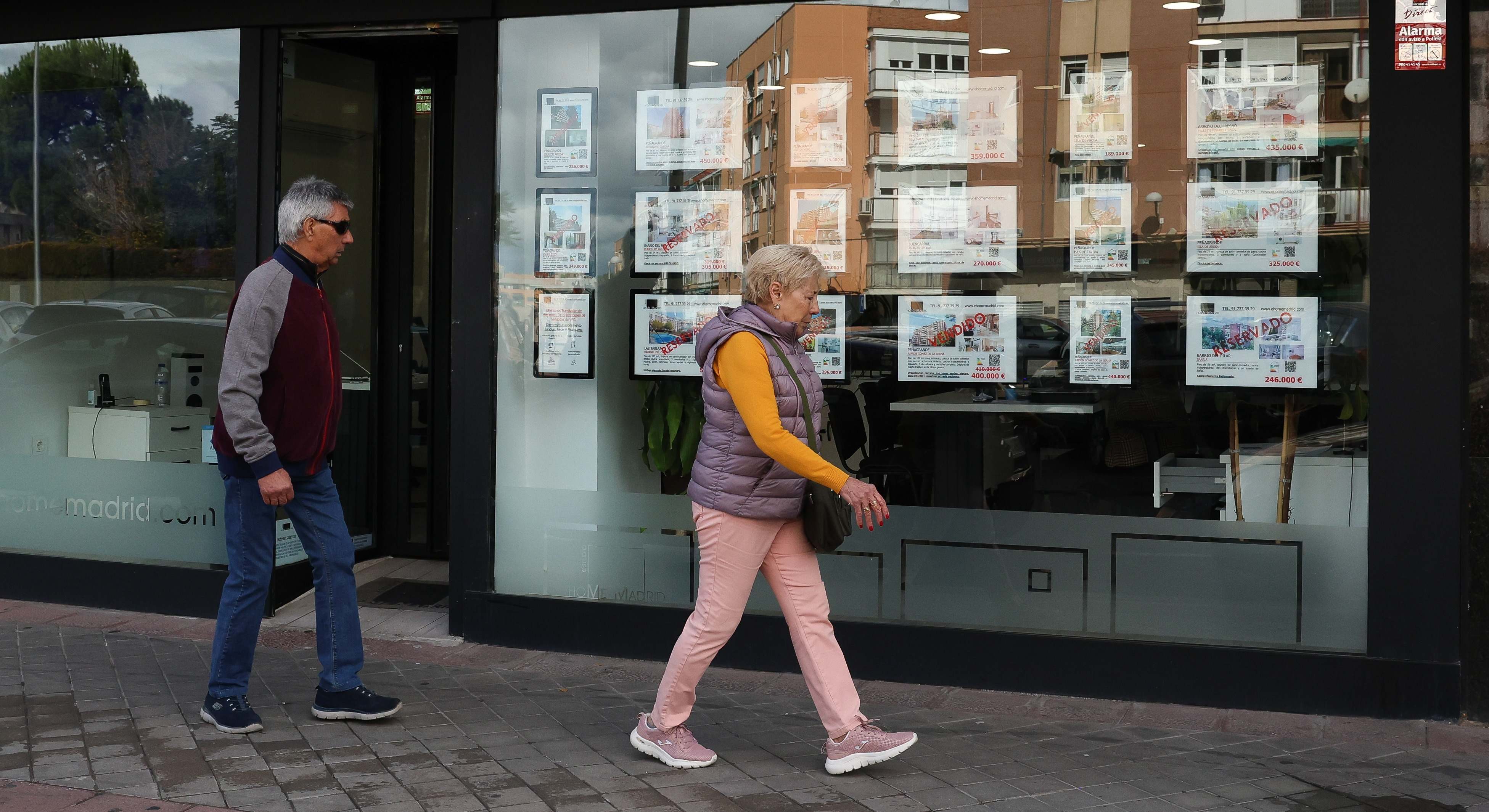 Personas pasando al lado de una inmobiliaria. Foto: Europa Press