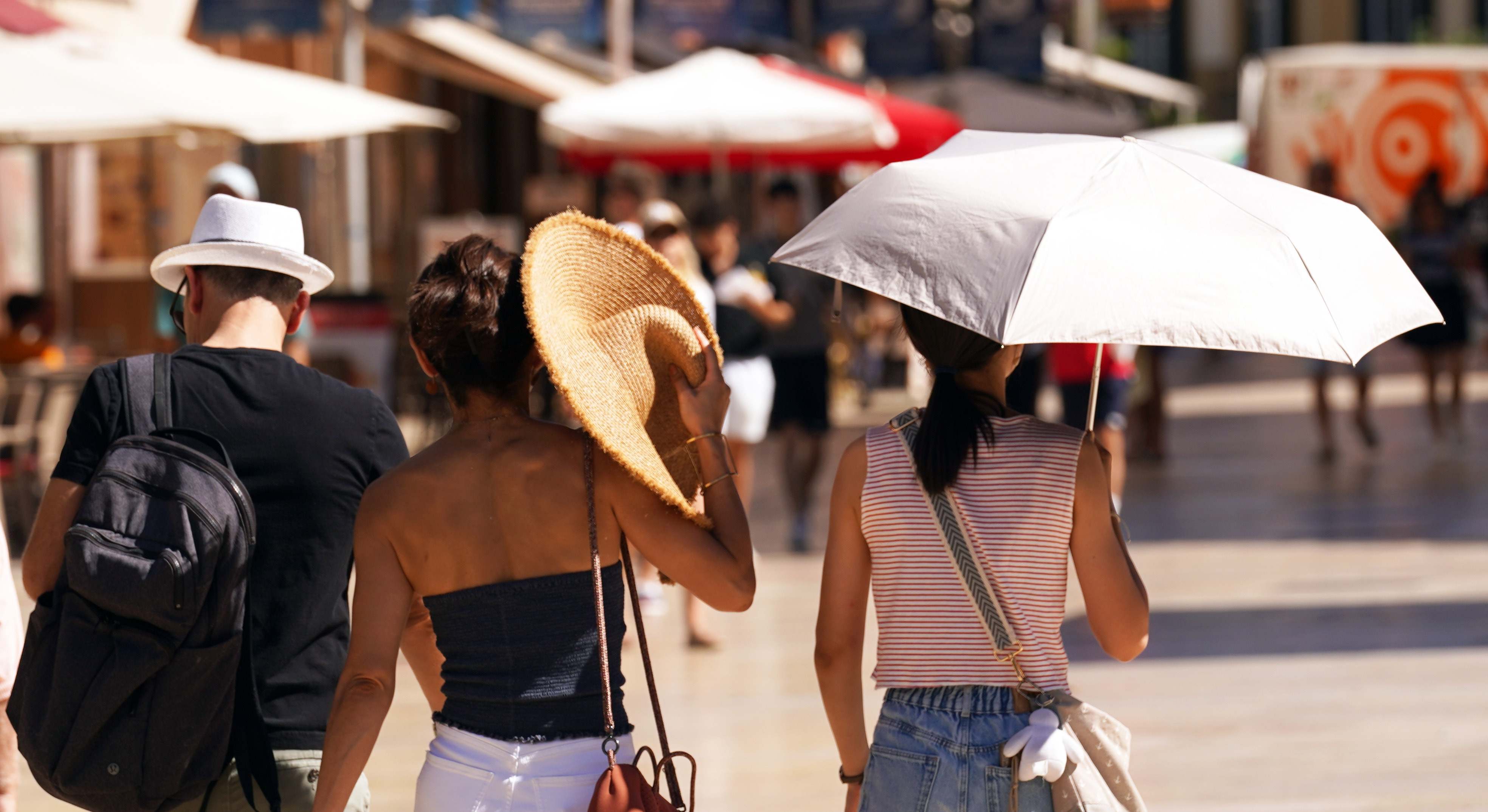 Turistas se protegen del sol con paraguas