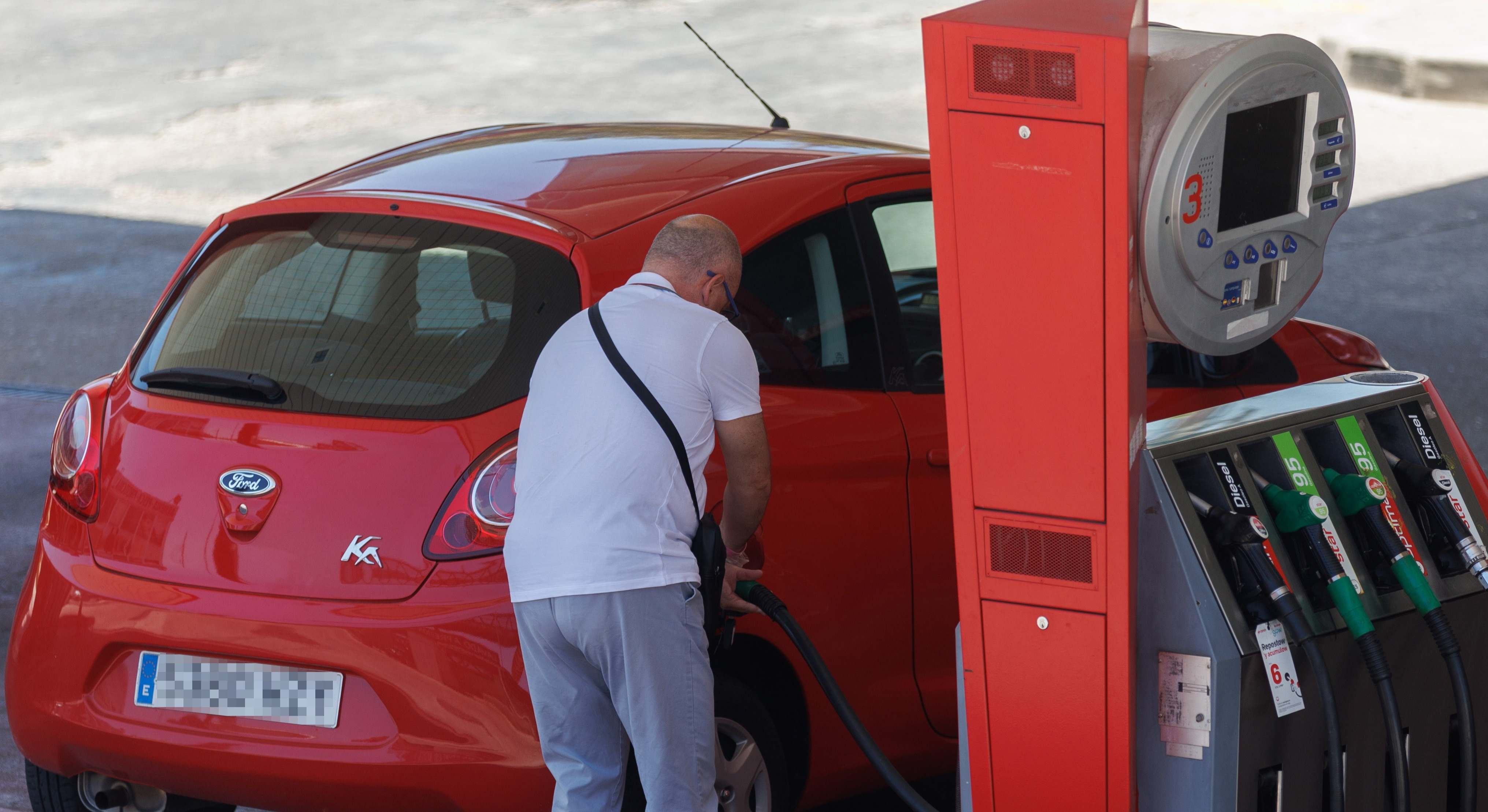 Un hombre echa gasolina en una estacón de servicio