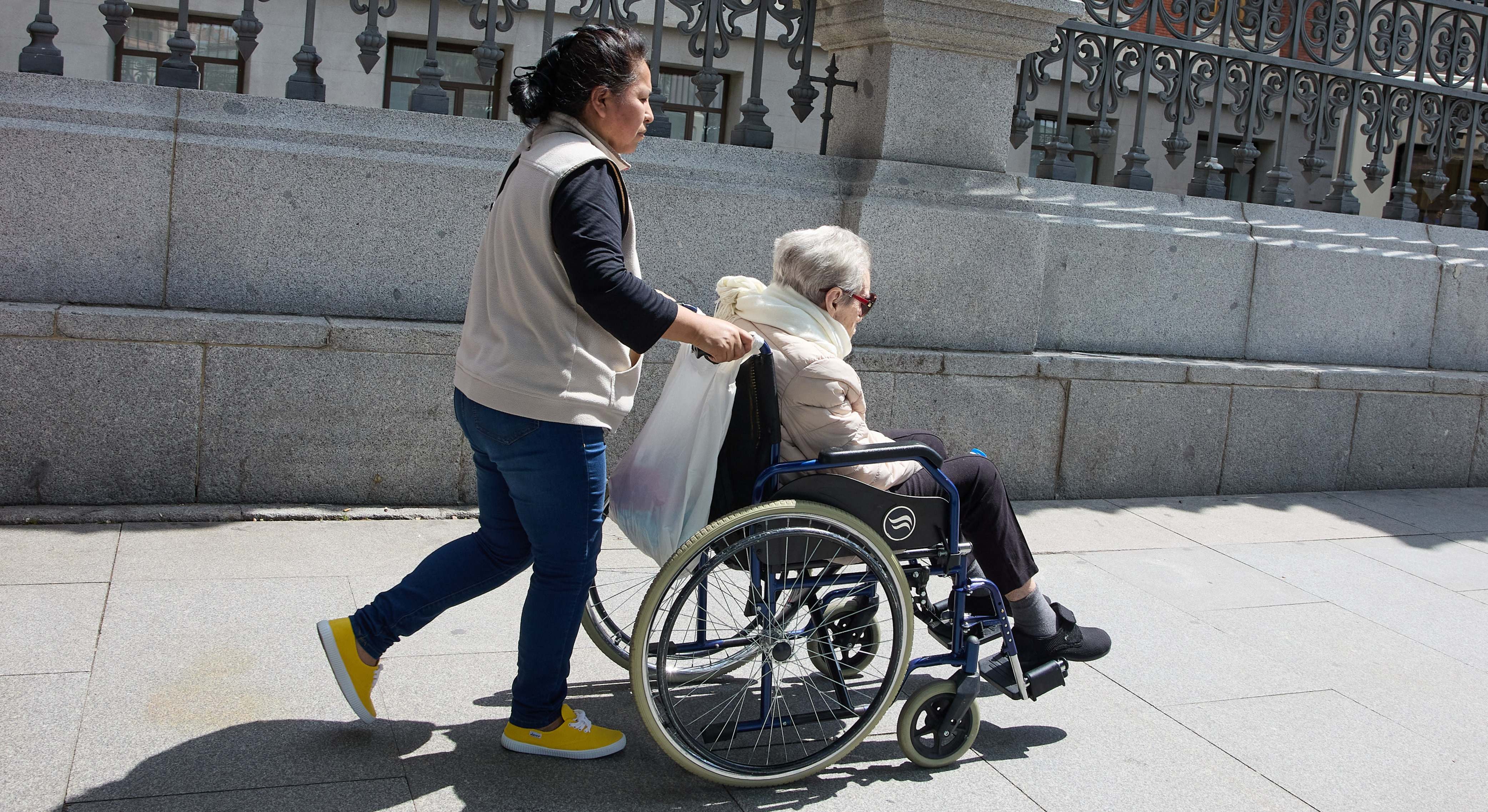 Una mujer mayor en silla de ruedas y su cuidadora dando un paseo