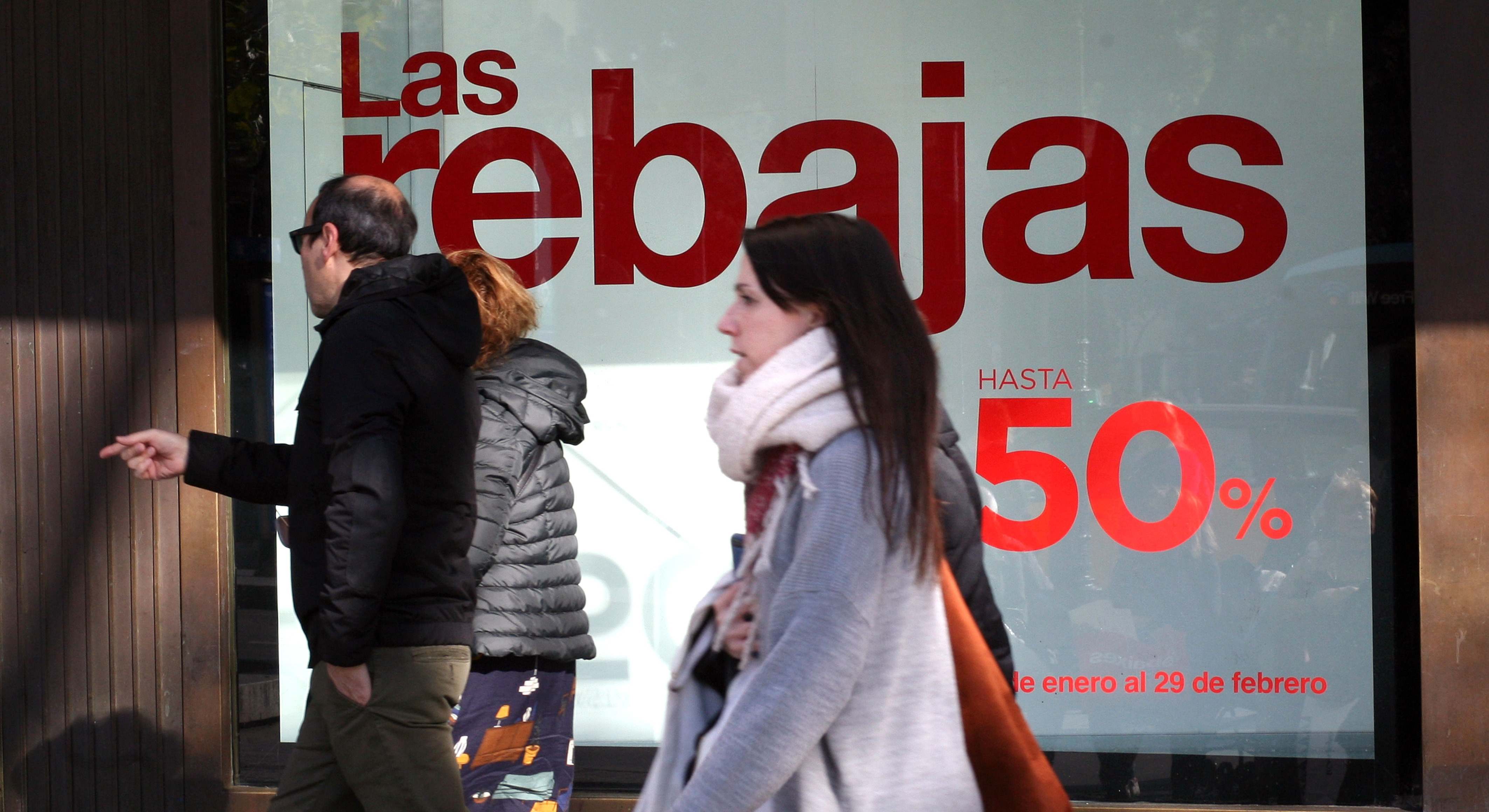 Varias personas pasan por delante de un cartel de rebajas