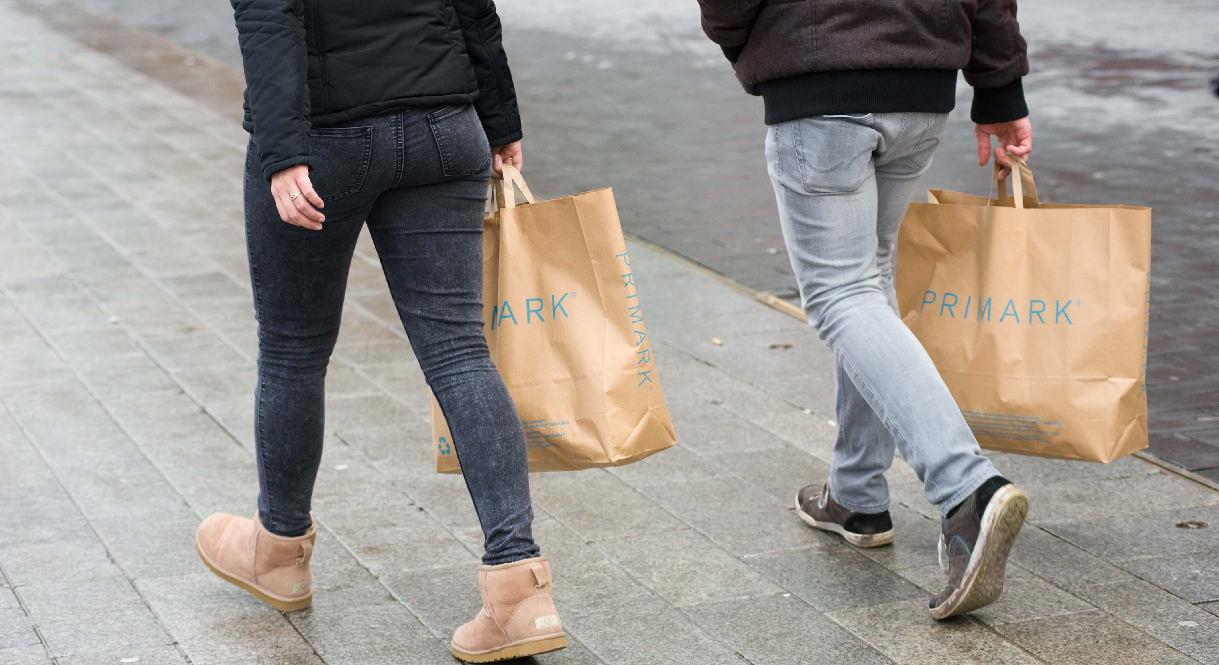 Dos personas por la calle llevando dos bolsas del Primark