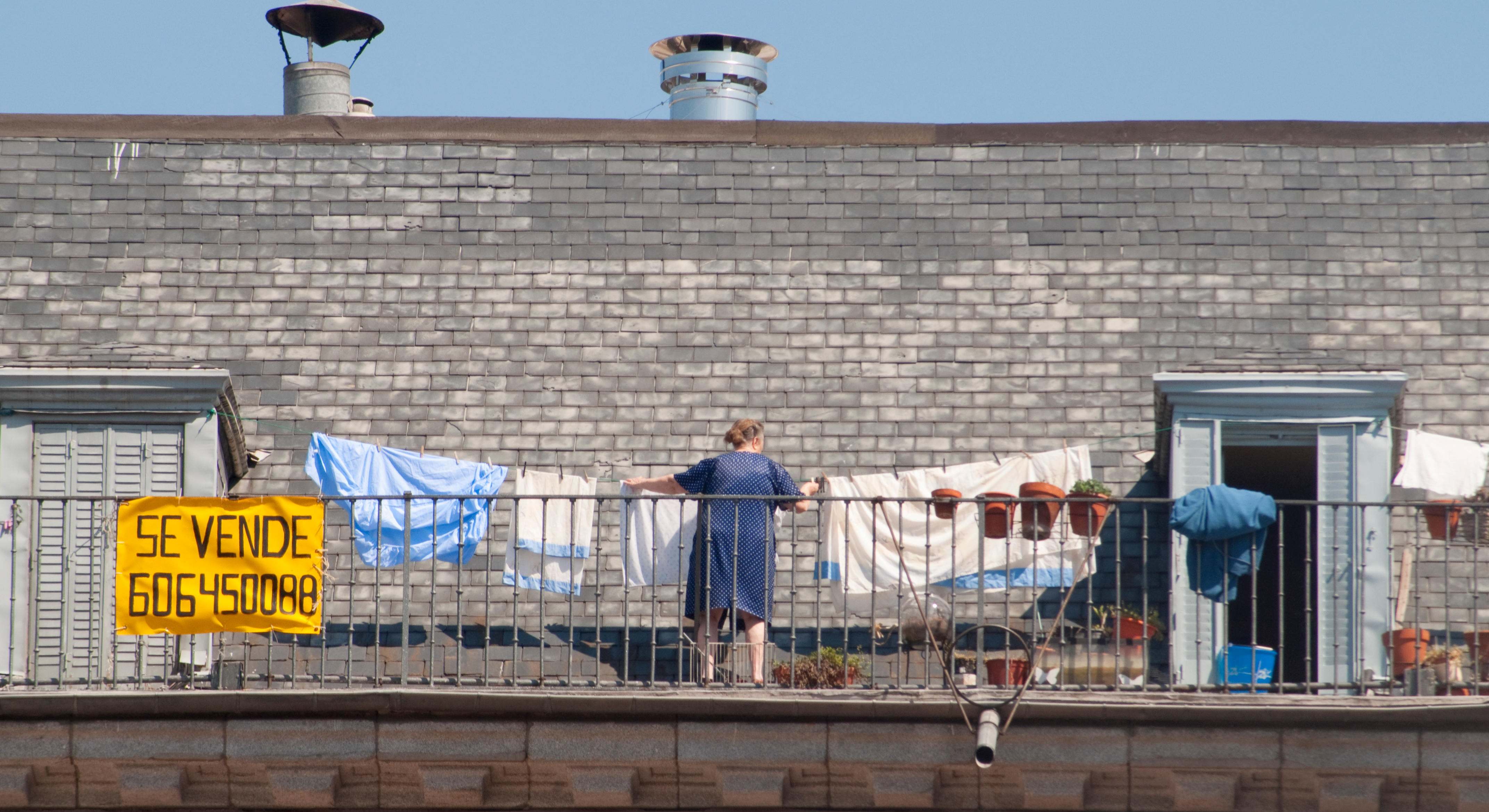 Mujer tendiendo la ropa en un ático en venta de la Plaza Mayor de Madrid. Foto: Alamy