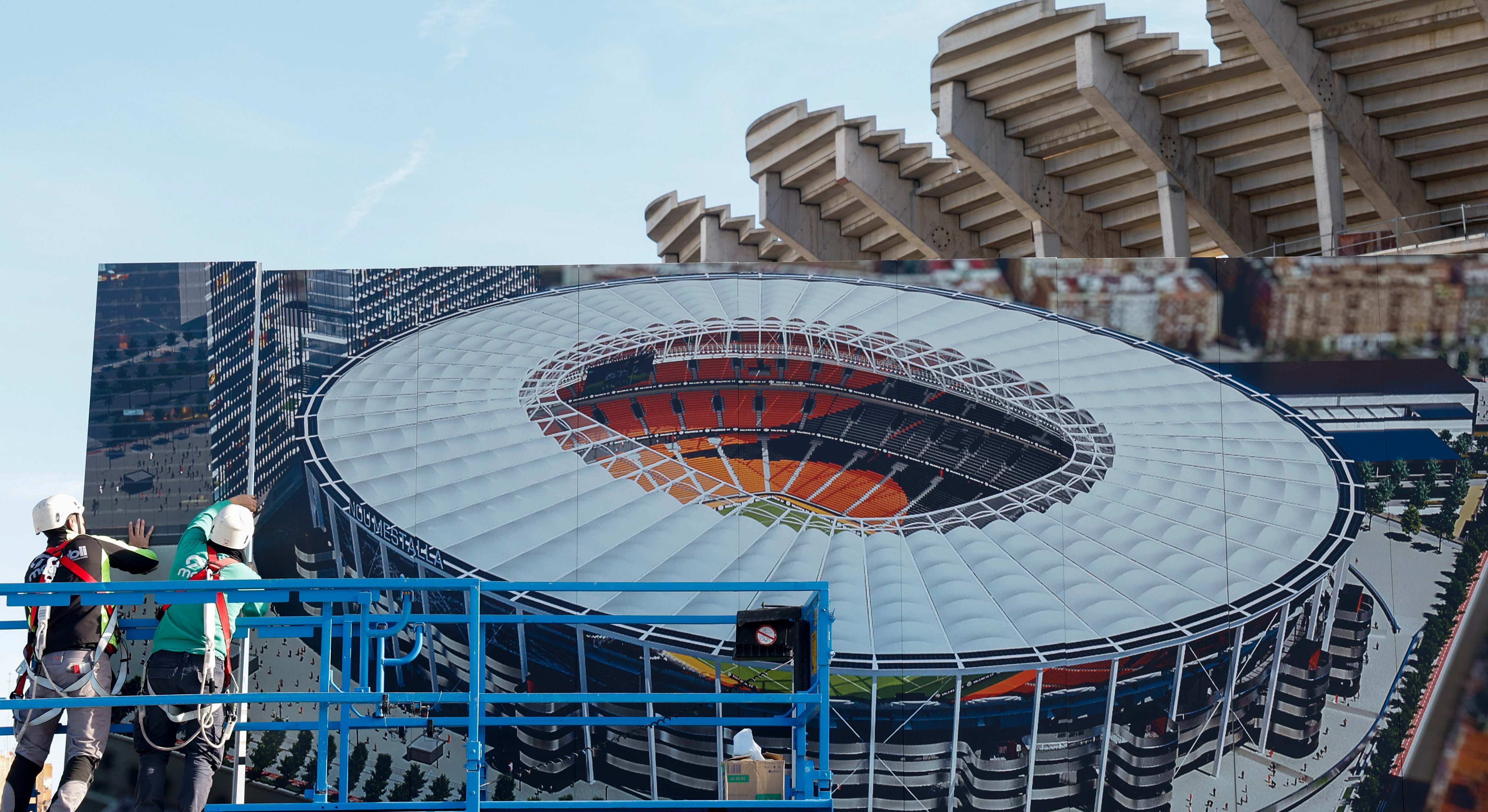 Unos operarios colocan un cartel del proyecto en el Nou Mestalla