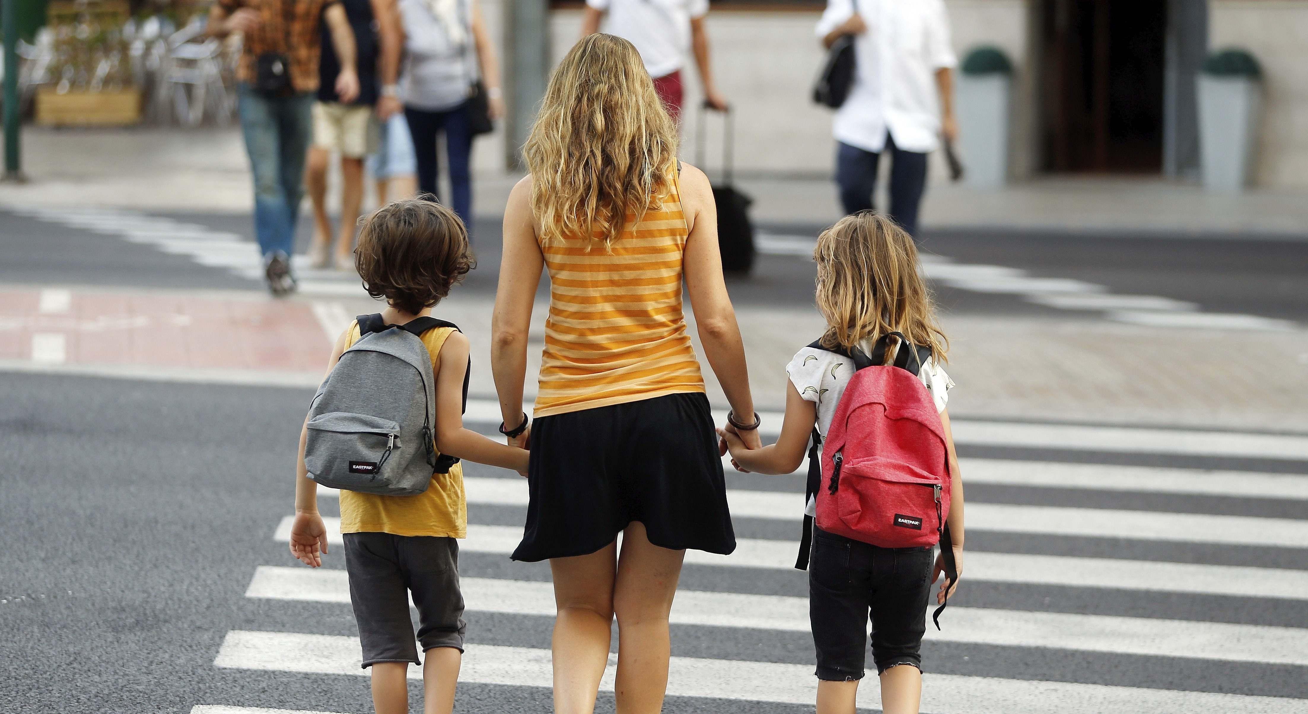 Una madre lleva a sus dos hijos al colegio