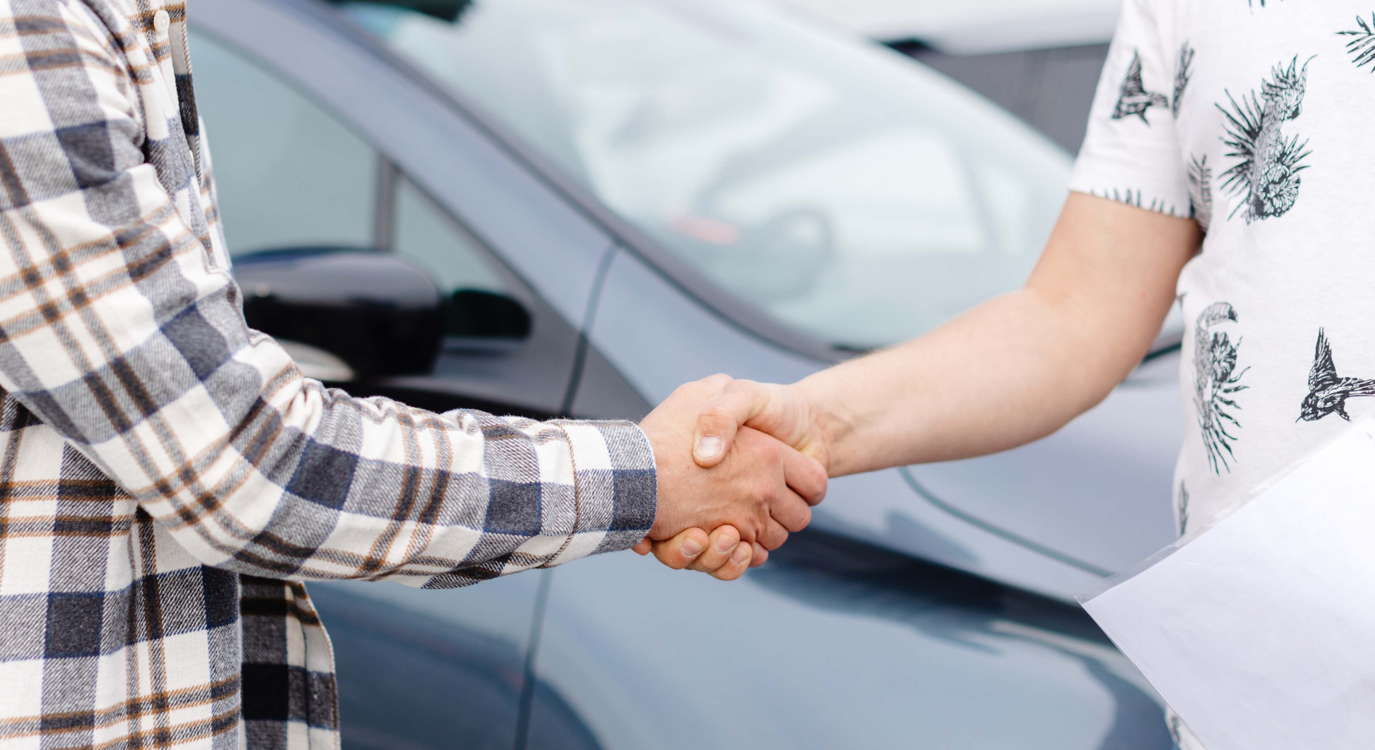Hombre comprando un coche y estrechando la mano con el vendedor