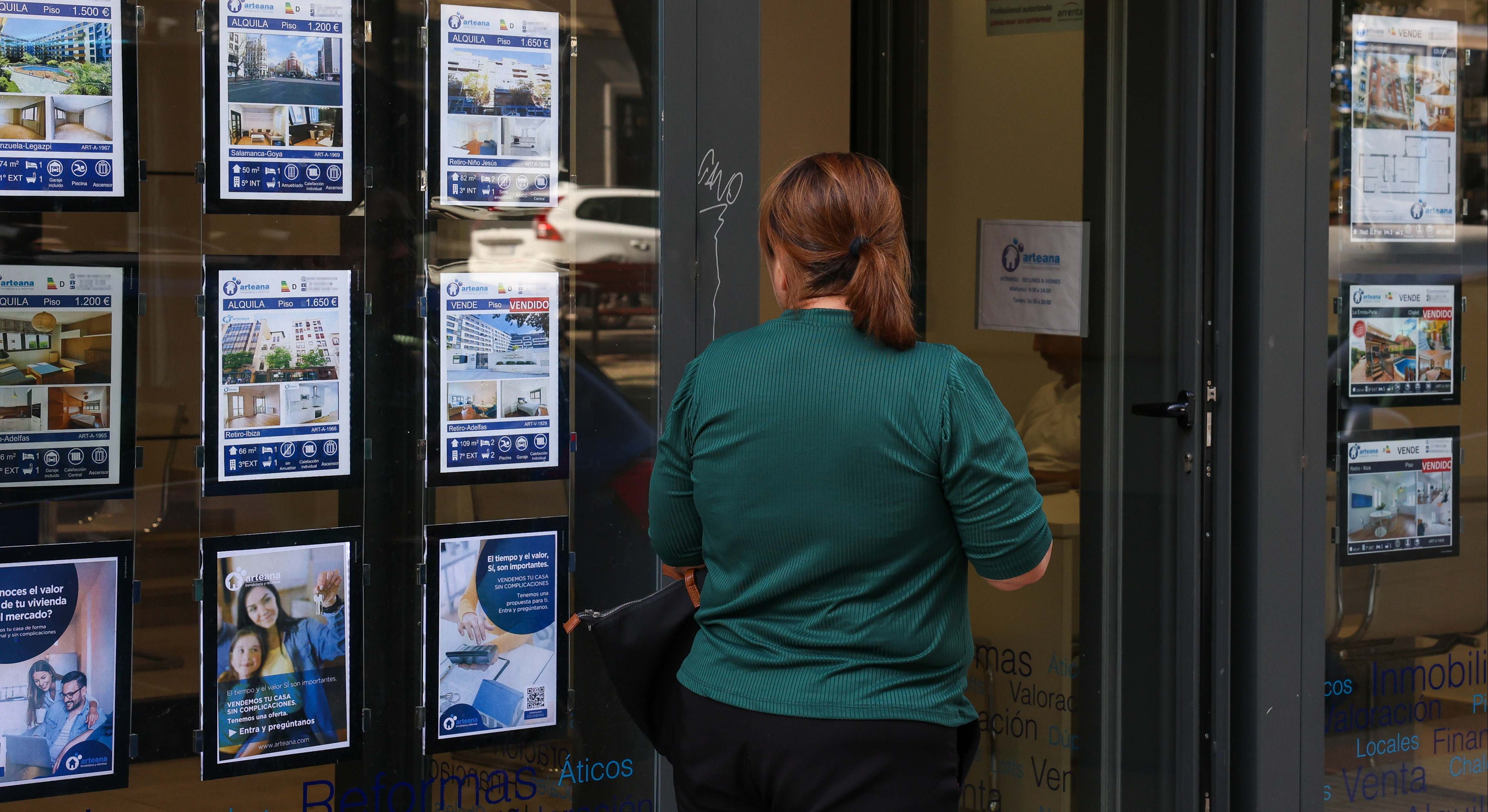 Imagen de una persona frente al escaparate de una inmobiliaria.
