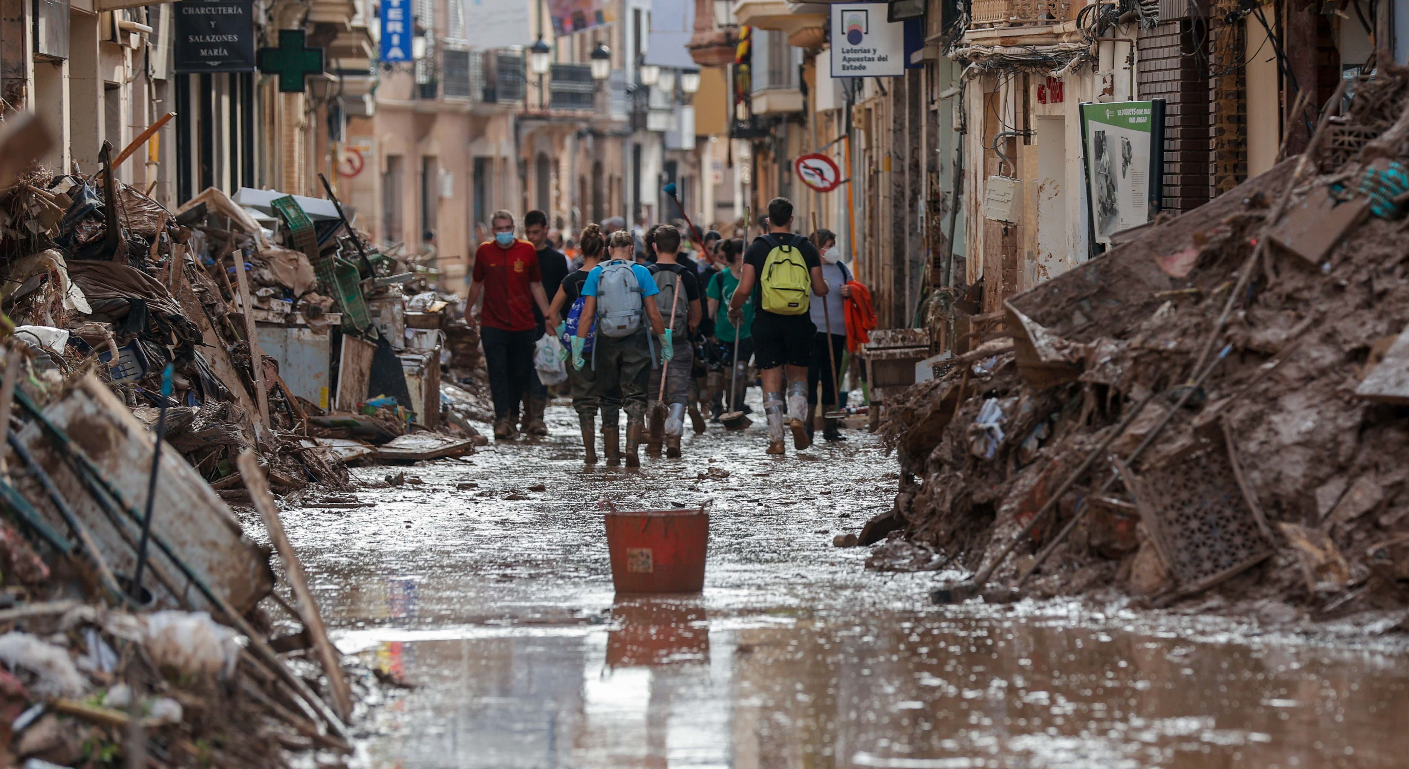Voluntarios limpian una calle de Paiporta arrasada por la DANA