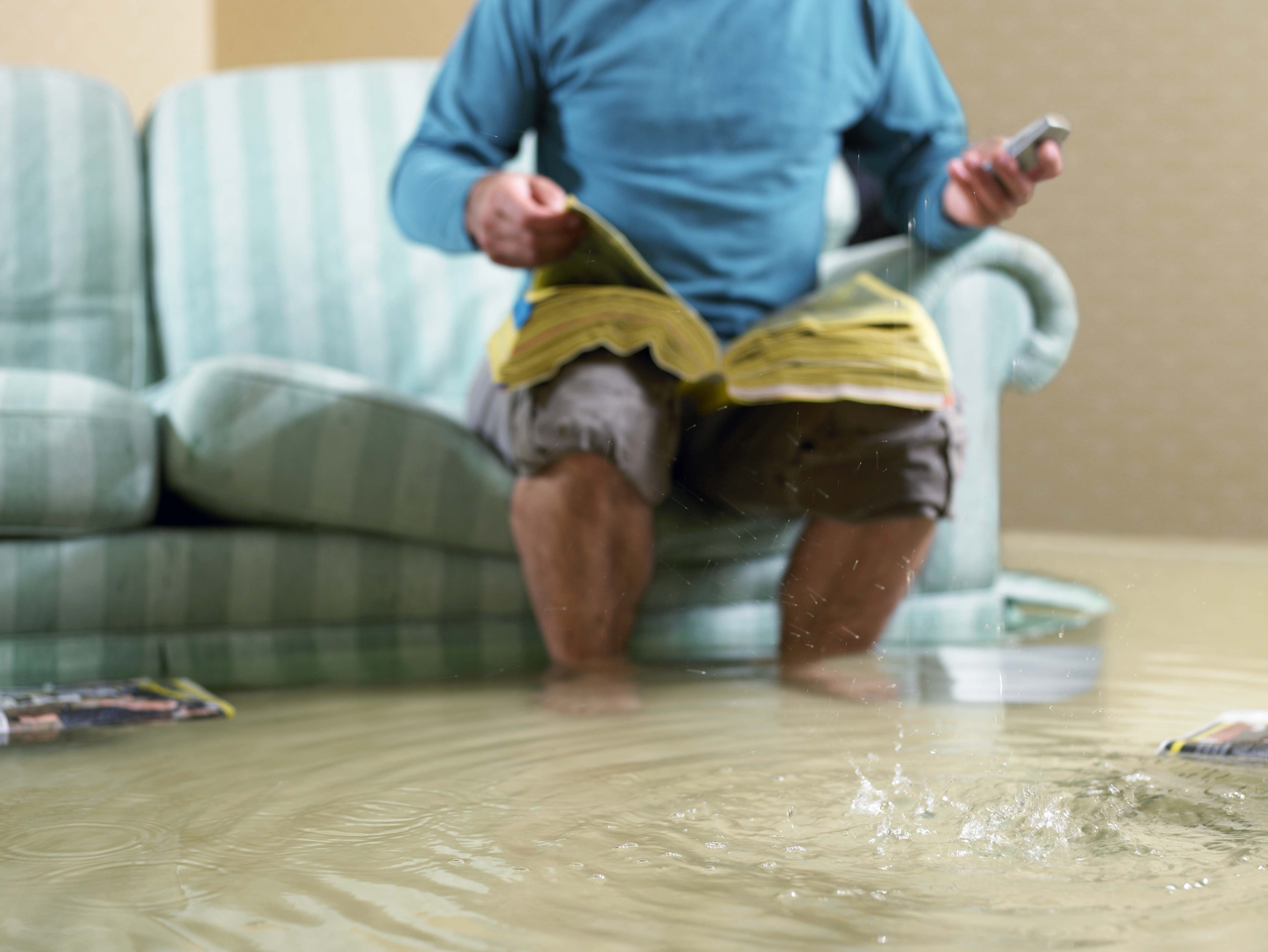 Hombre en el sofá con agua por las rodillas