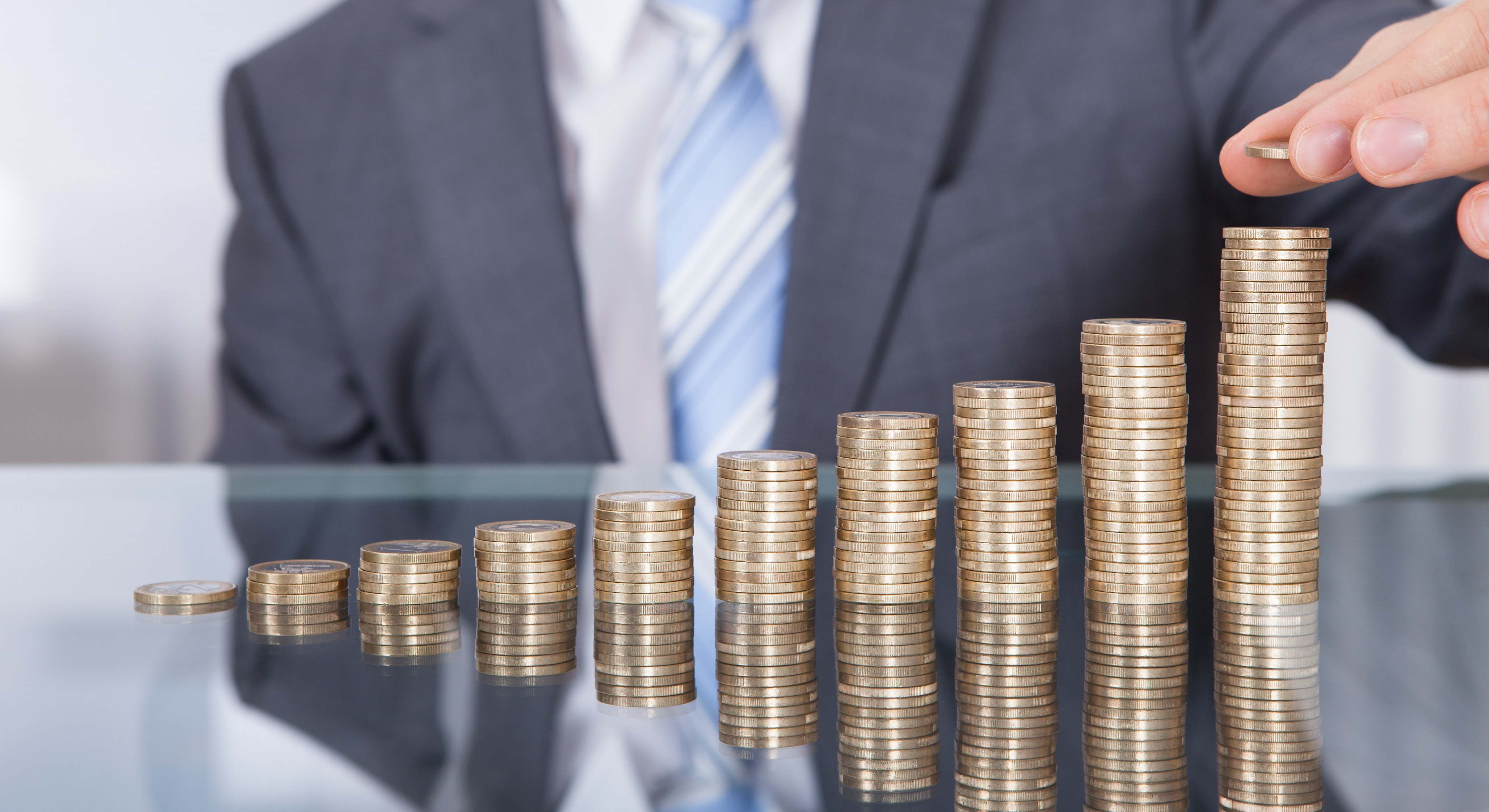 Un hombre en traje pone una moneda en una montaña creciente de monedas