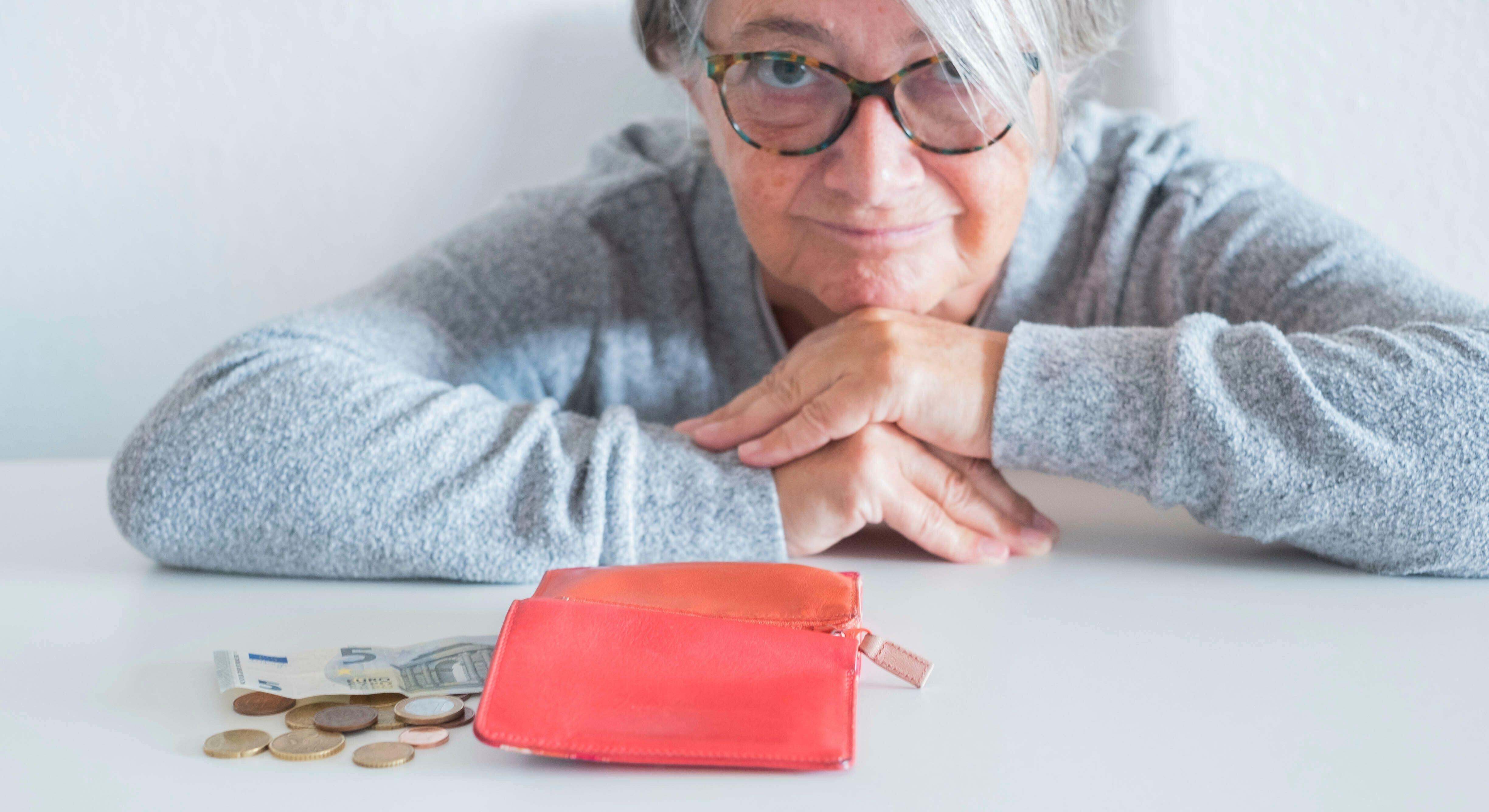 Una mujer mayor con una cartera y dinero sobre la mesa